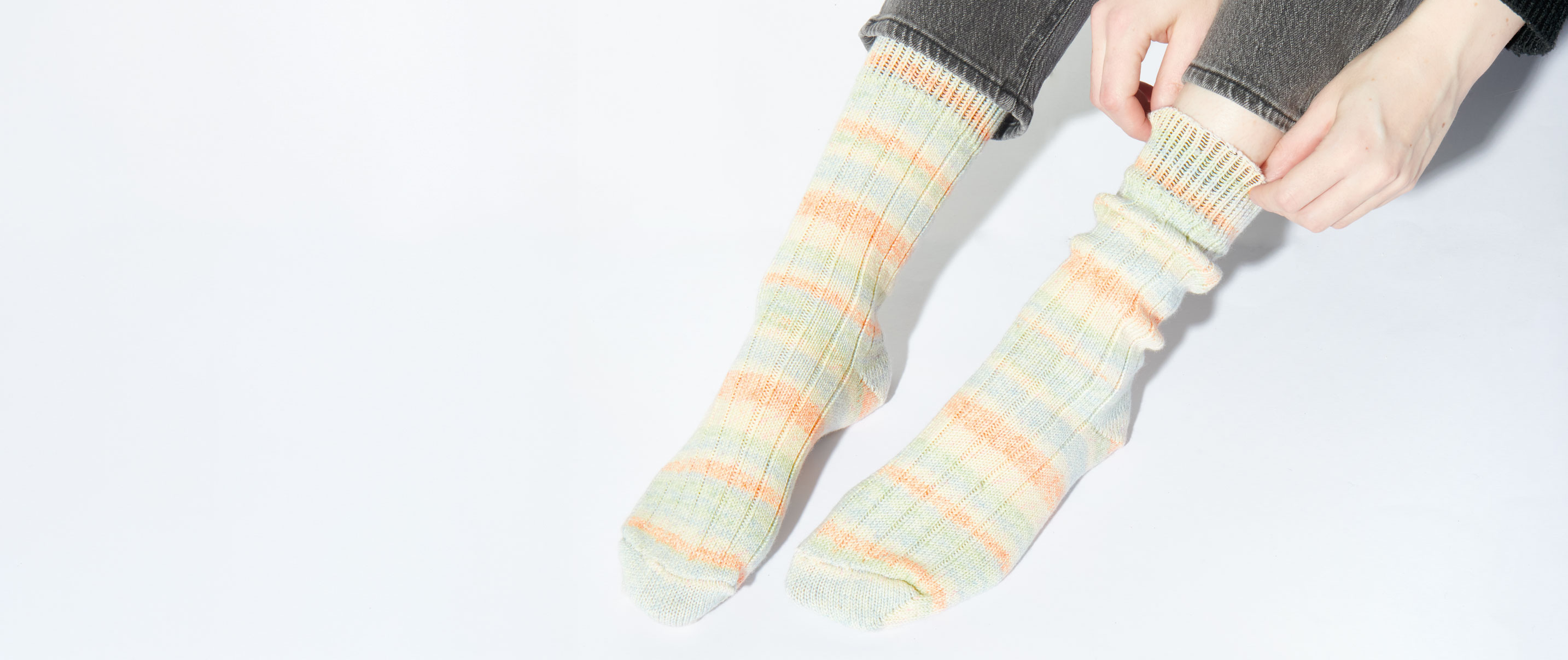 Frau trägt pastellfarbene Stricksocken an den Füßen