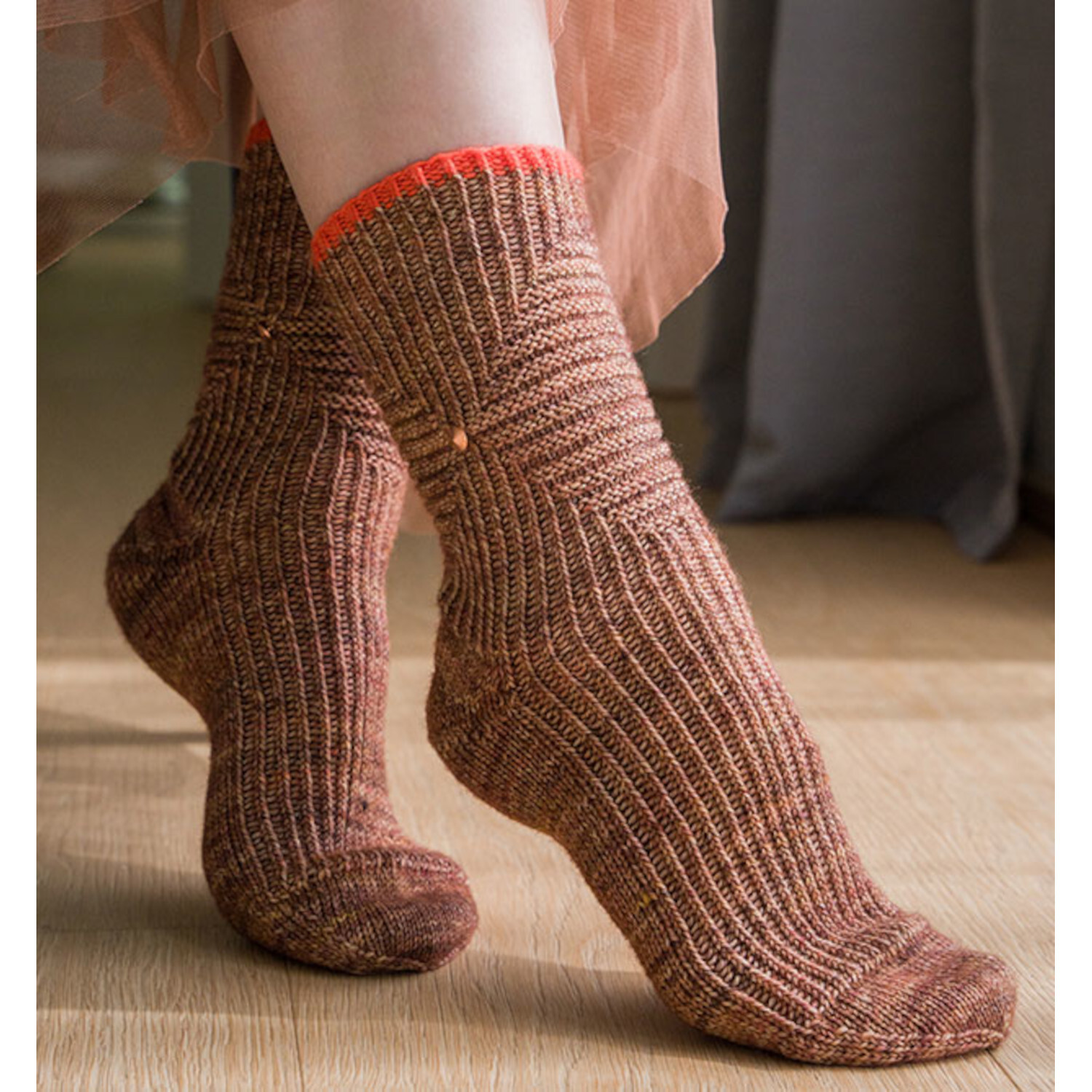 Sockenliebe Tanja Steinbach: Braune Stricksocken mit rotem Rand, getragen auf Holzboden.