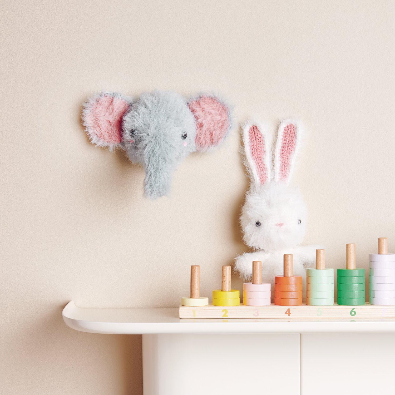 Creative Ricorumi dk 25g Farbe Creme von Rico Design Ricorumi Furry Animals: Flauschiger Elefant und Hase aus Wolle, dekorativ auf Regal mit bunten Holzspielzeugen.