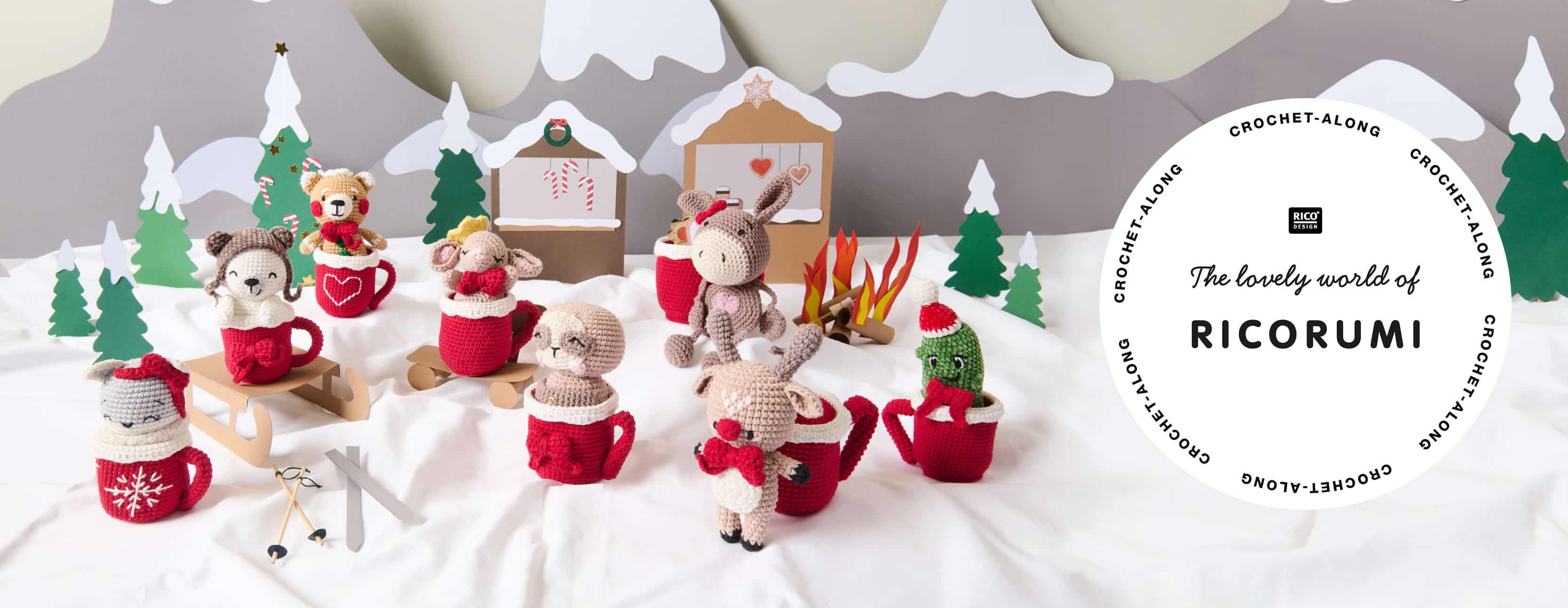 Acht Amigurumis mit gehäkelten Tassen sind in einer aus Papier gestalteten Winterlandschaft dekoriert. Ein Logo von Ricorumi ist abgebildet.