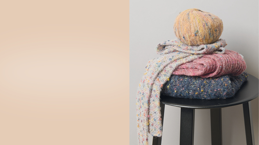 Auf einem Hocker liegen verschiedene gestrickte Stücke zusammen mit einem Garnknäuel, daneben ein Farbausschnitt.