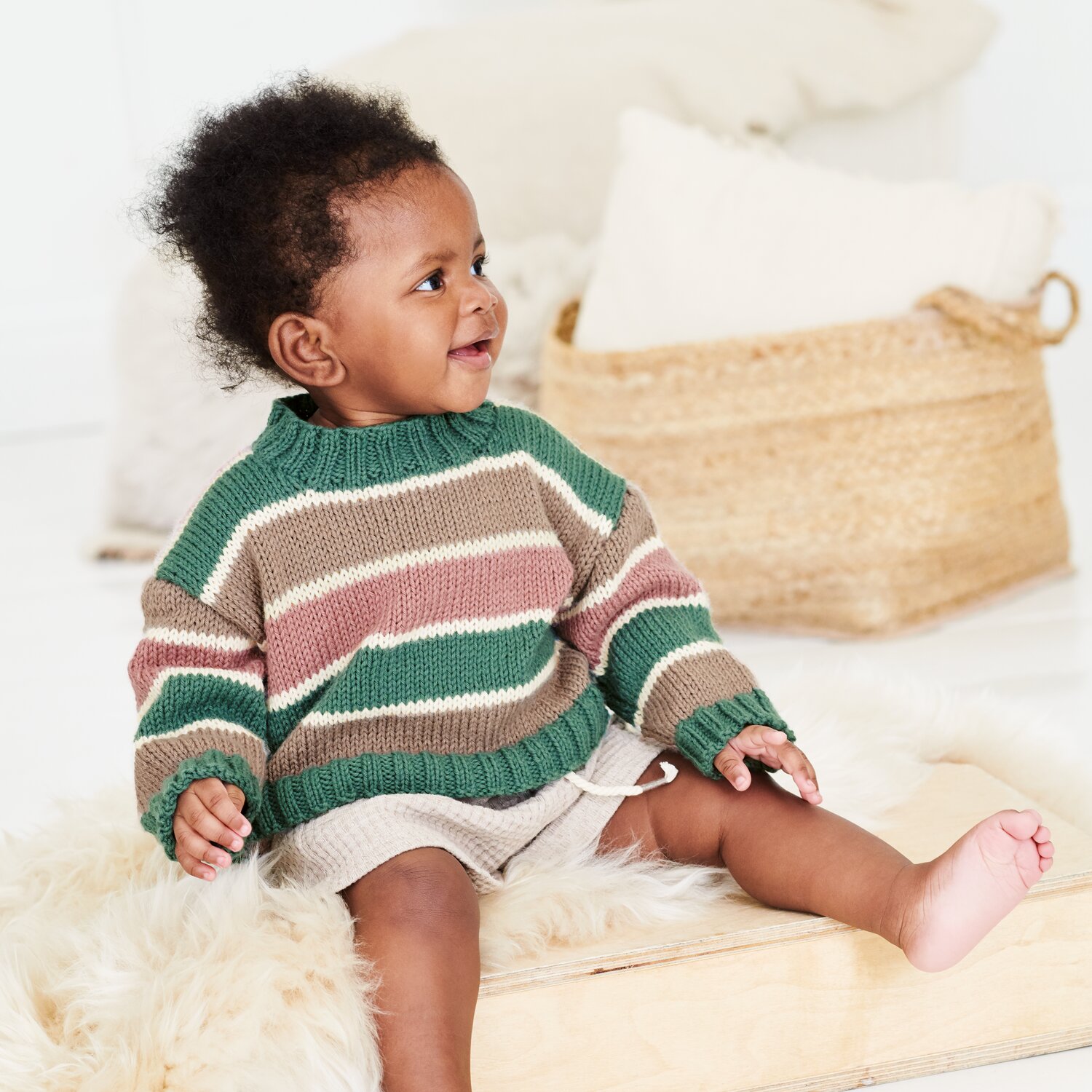 Strickset Pullover Modell 22 aus Baby 044, gestreifter Kinderpulli mit lockerer Passform, weichem Material und breiten Blockstreifen, getragen von sitzendem Baby