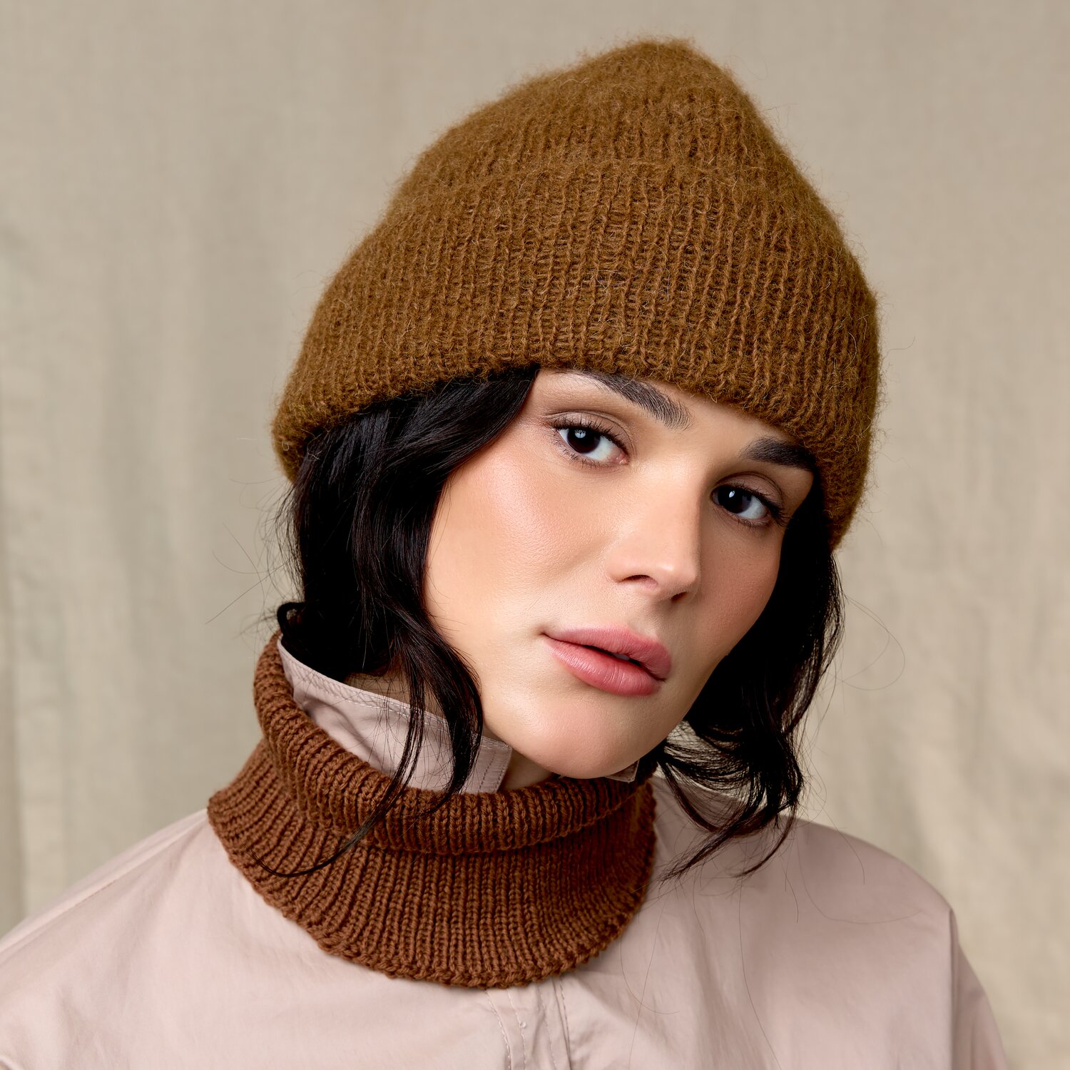 Strickset Mütze Modell 10 aus Luxury Knits Little Pieces, weiche winterliche Wollmütze mit passendem gestricktem Halswärmer in warmem Braunton an junger Frau