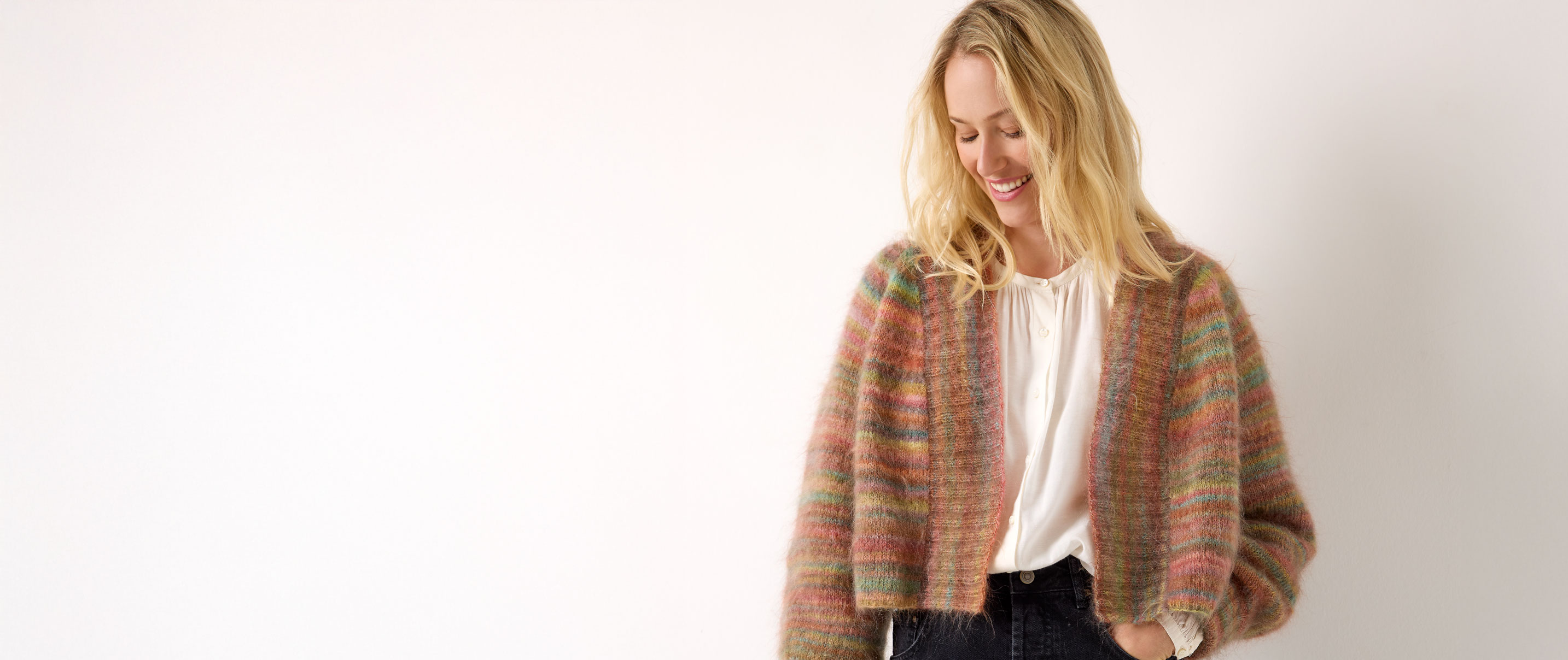 Frau trägt eine bräunliche Strickjacke mit Farbverlauf vor einem neutralen Hintergrund