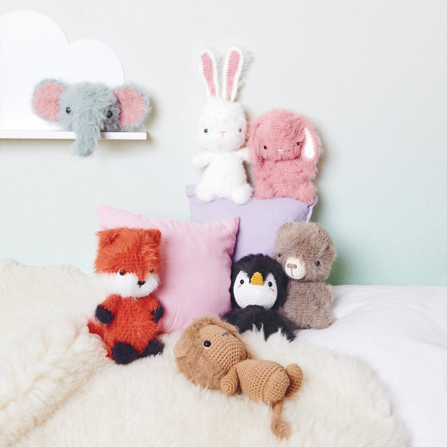Creative Ricorumi dk 25g Farbe Fuchs von Rico Design Ricorumi Furry Animals: Kuschelige Stofftiere in verschiedenen Farben auf einem weißen Bett arrangiert.