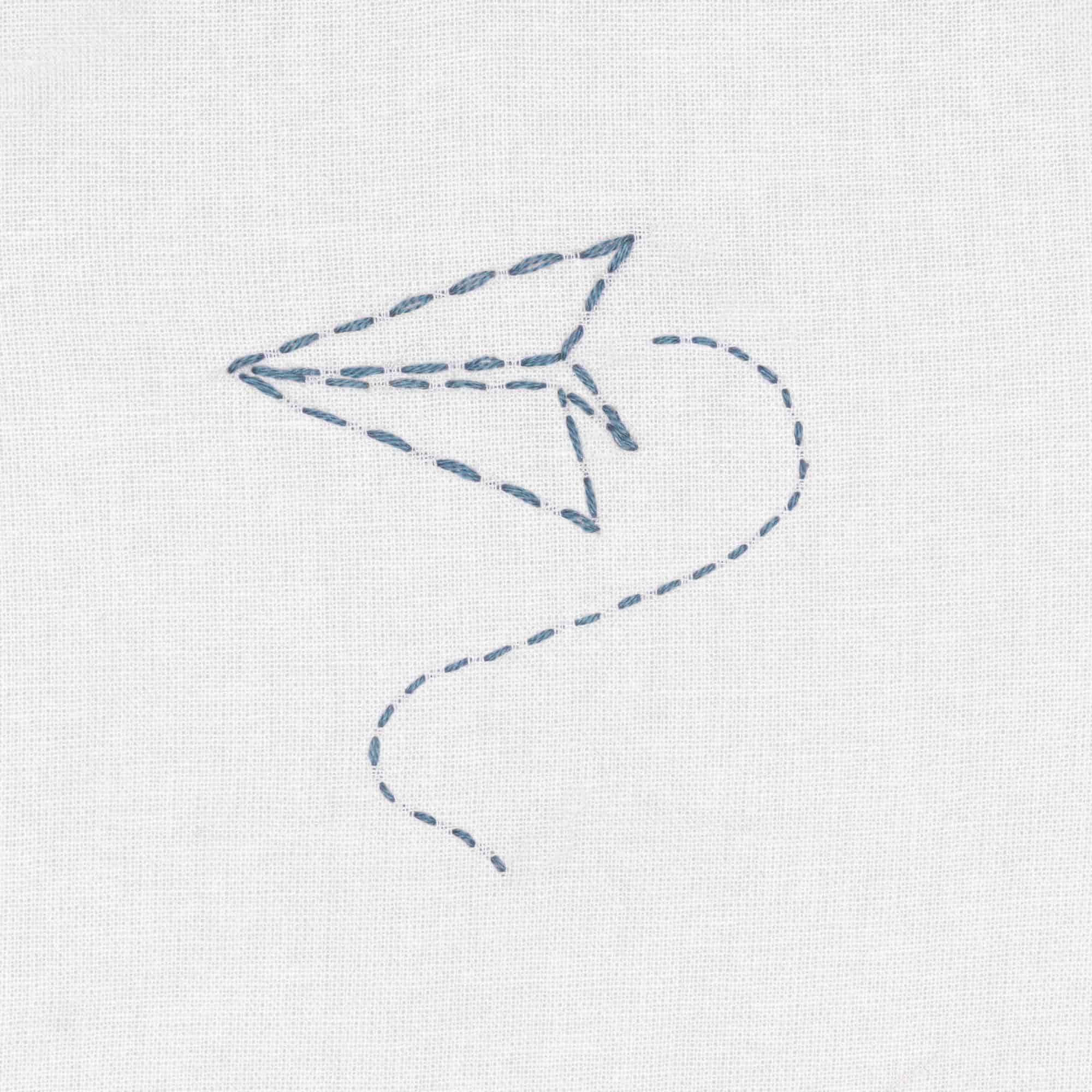 Der Umriss eines blauen Papierfliegers ist im Vorstich auf weißen Stoff gestickt
