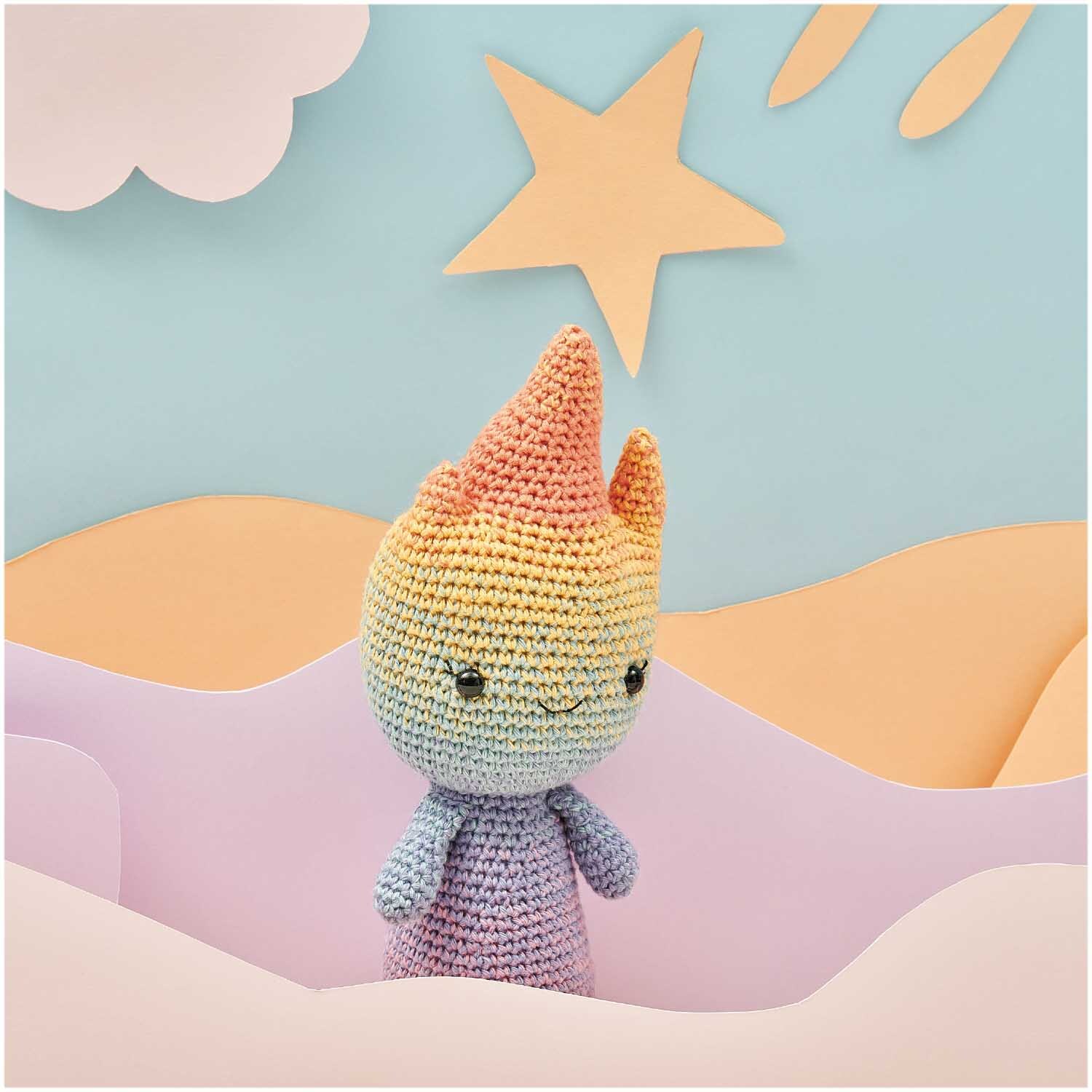 Ricorumi Spin Spin dk: Gehäkelte Figur in Pastelltönen vor einem Hintergrund mit Stern und Wolken.