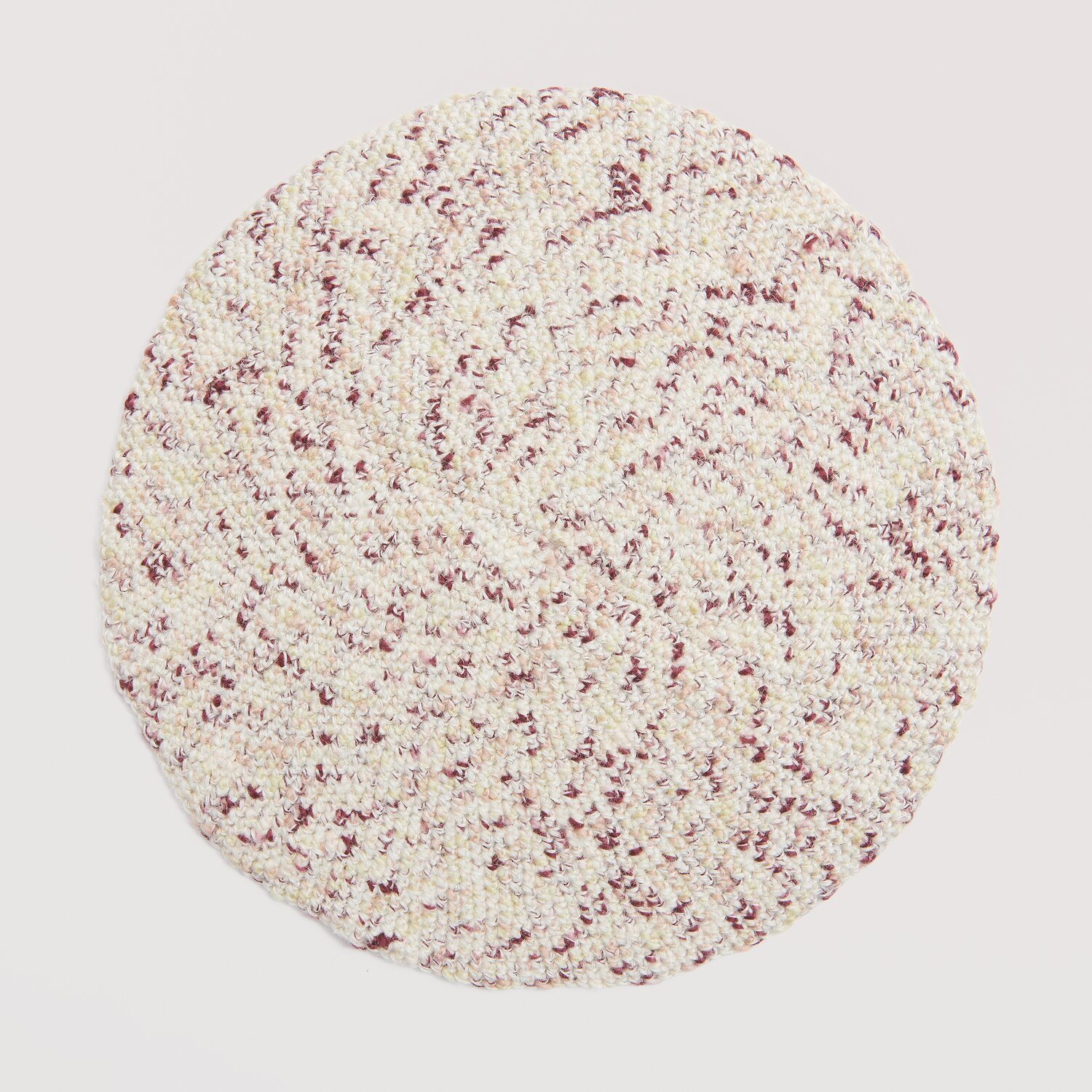 Creative "Hey Jute": Runde, gestrickte Unterlage in Creme und Rot, ideal für stilvolle Dekoration.