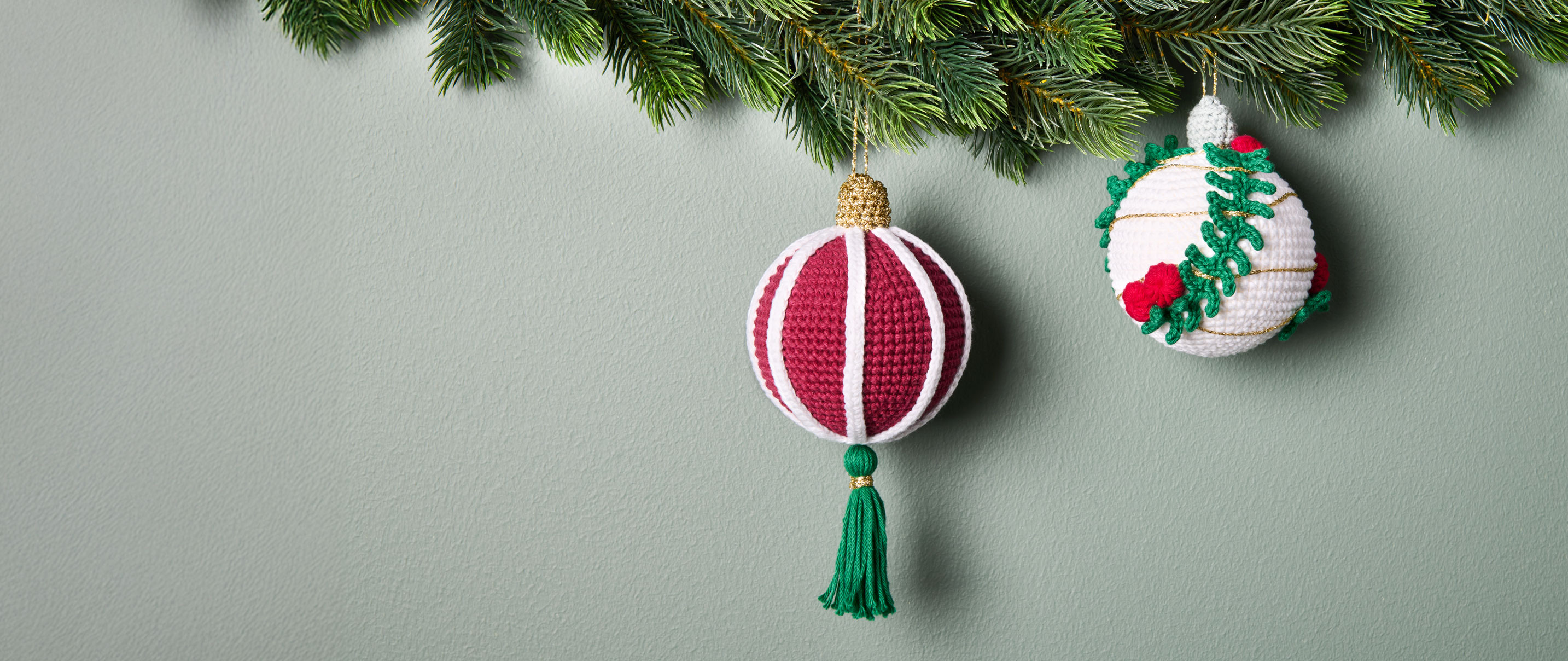 Gehäkelte Weihnachtskugeln hängen an Tannengirlande