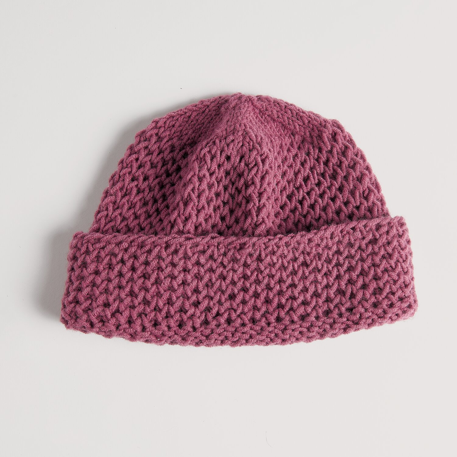 Strickset Mütze Modell 10 aus Die Neue Masche No. 16 Herbst von Wolle Rödel, grob gestrickte Beanie mit breitem Umschlag, liegend vor hellem Hintergrund