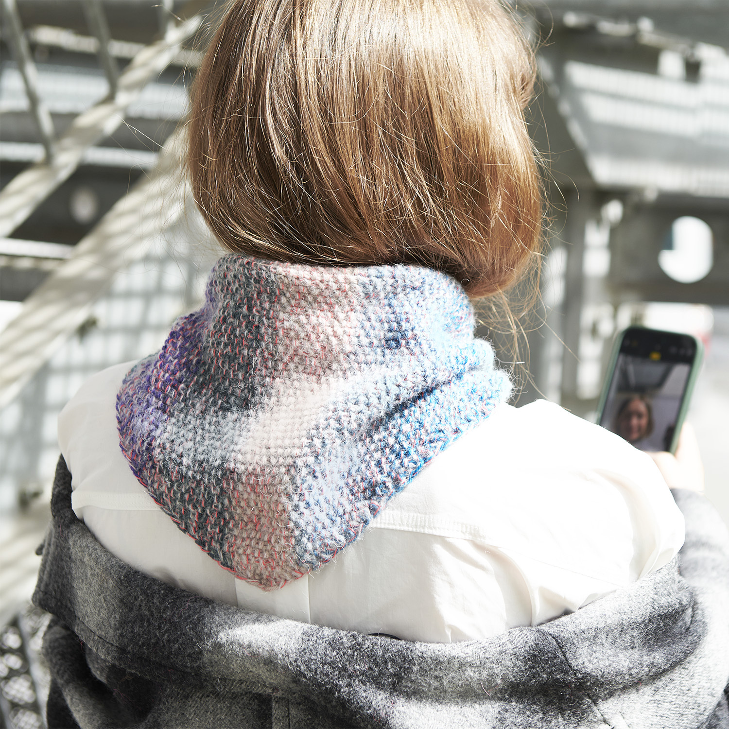 Strickanleitung Mini Dreieckstuch mit Pastellverlauf: Frau mit pastellfarbenem Tuch, das über einer weißen Bluse getragen wird.