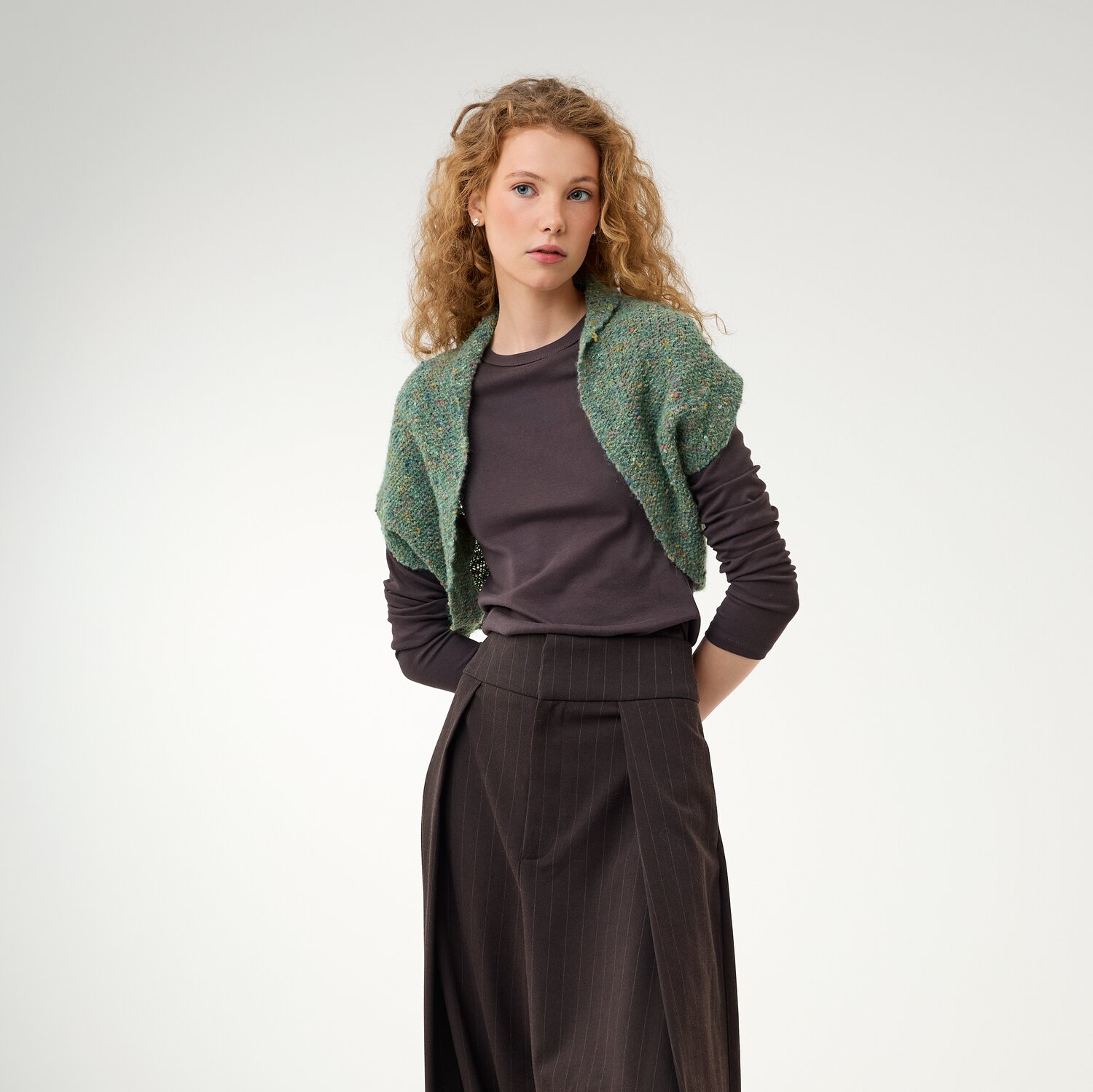 Strickset Weste Modell 12 aus Die Neue Masche No. 16, kurz geschnittene Strickweste über langärmligem Oberteil, kombiniert mit weiter Hose vor hellem Hintergrund
