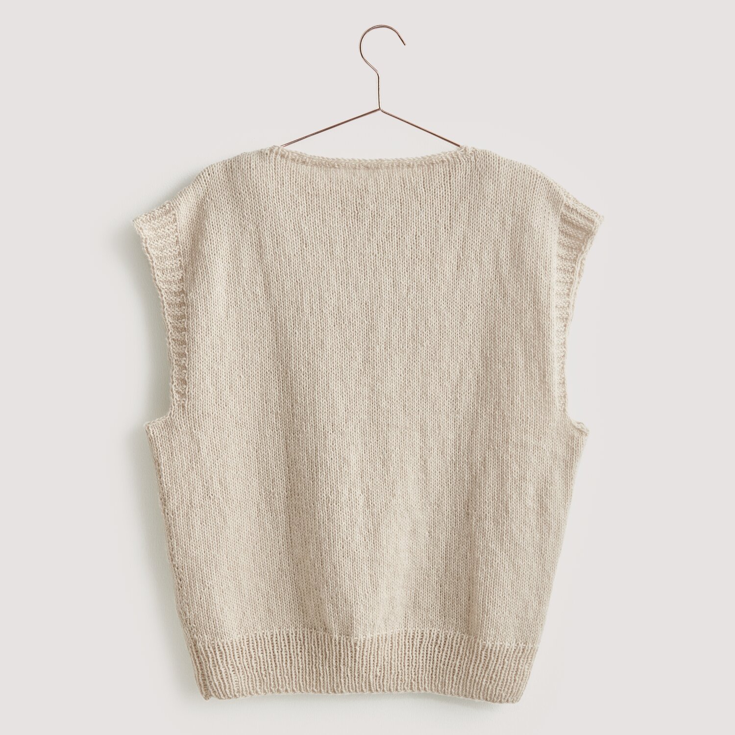 Luxury Merino Supercash dk: Ärmelloser Pullover in Naturfarbe, aus Premium-Naturfasern, auf einem Kleiderbügel.