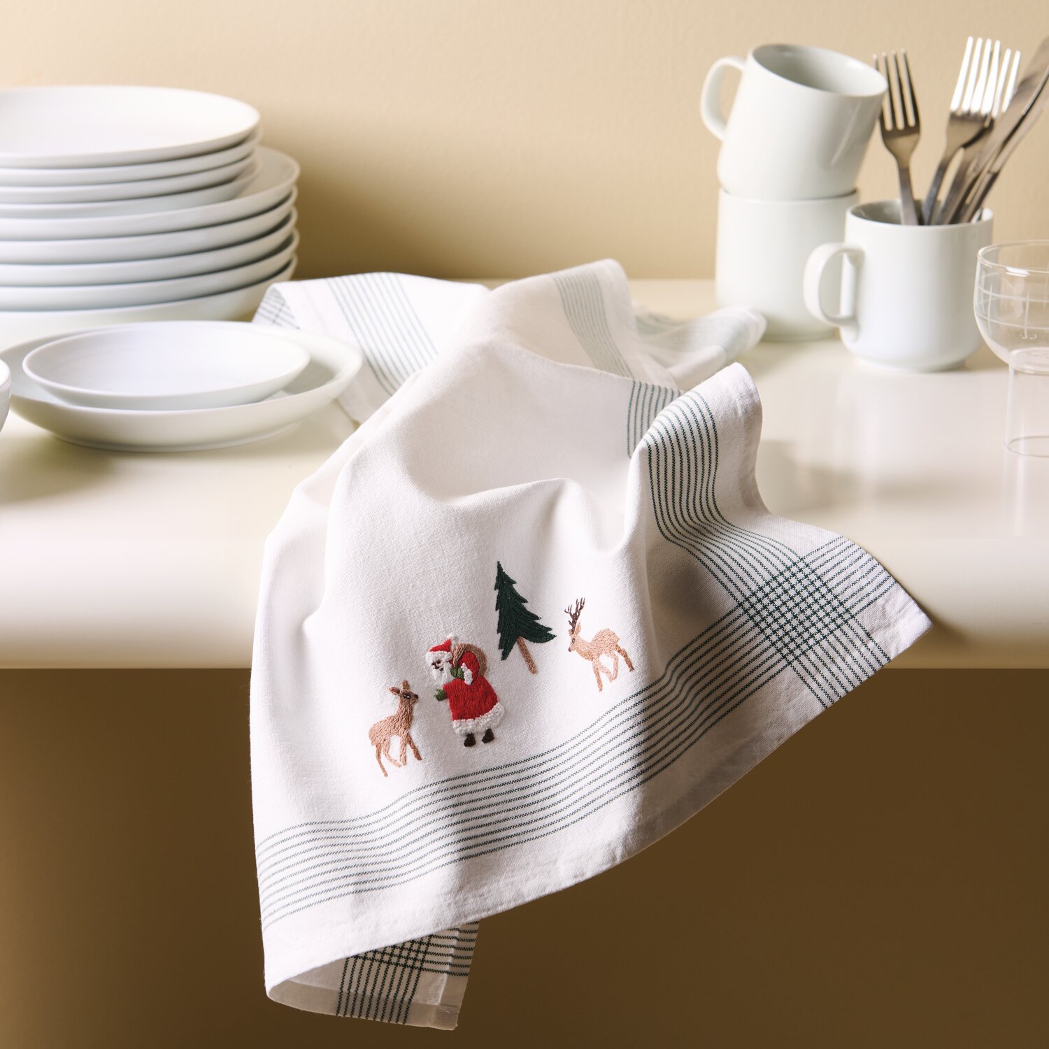 Stick & Stitch Stickpackung Weihnachtswald 12 Stück zeigt ein weißes Geschirrtuch mit Weihnachtsmotiven, ideal für festliche Dekorationen.