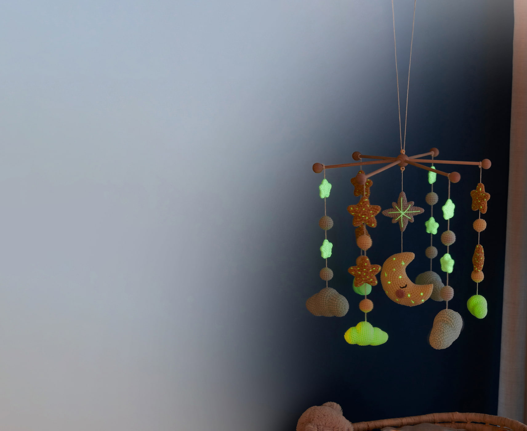 Mobile mit gehäkelten Sternen, Wolken, Kugeln und Mond hängt in einem dunklen Raum