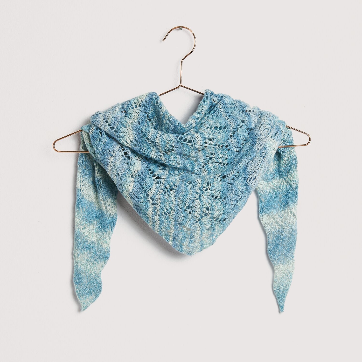 Die Neue Masche No. 12 Frühjahr-Sommer von idee. Creativmarkt Strickset Dreieckstuch Modell 25 in Blau auf einem Kleiderbügel. Aus Die Neue Masche No. 12.