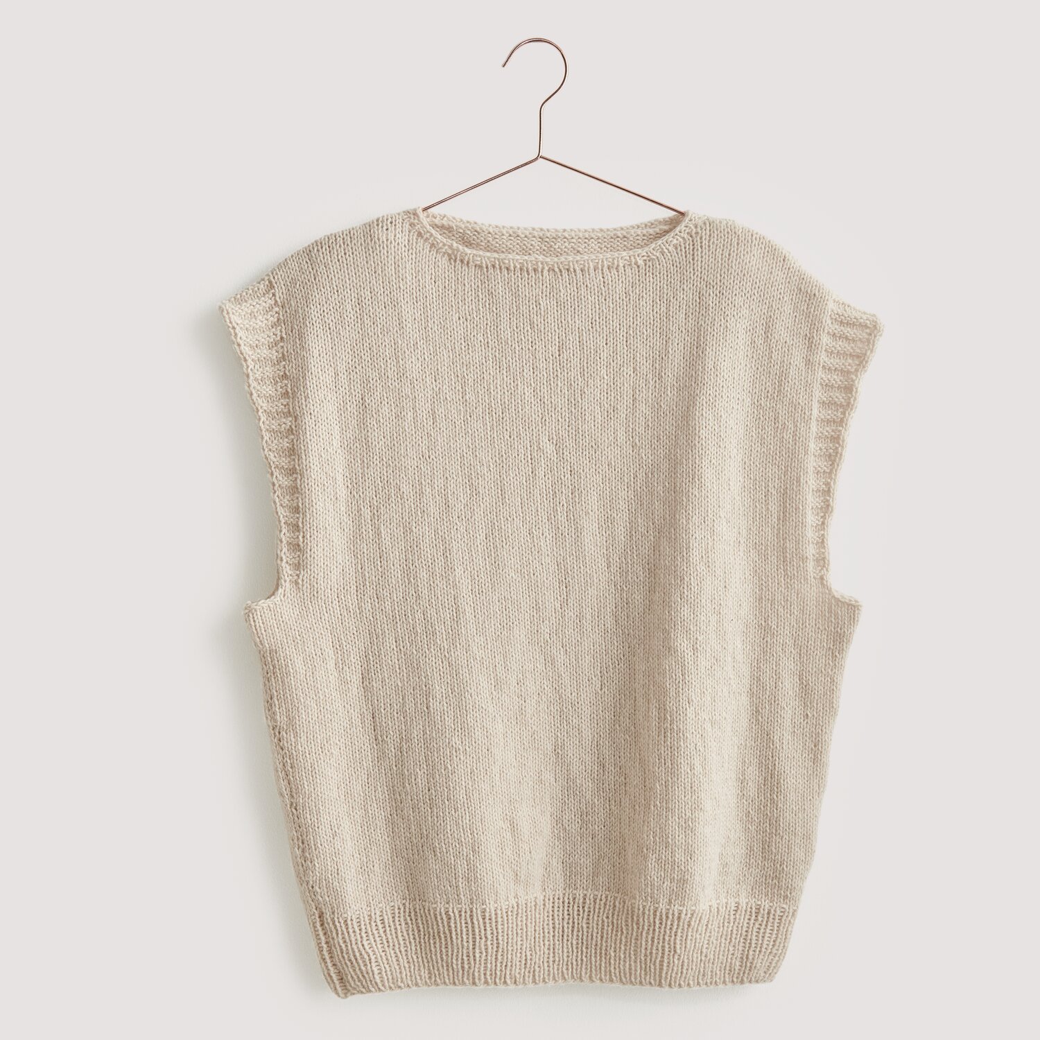 Strickset Pullunder Modell 03 aus Luxury Knits: Beiger Pullunder aus Premium Natural Fibres, hängend an einem Kleiderbügel.
