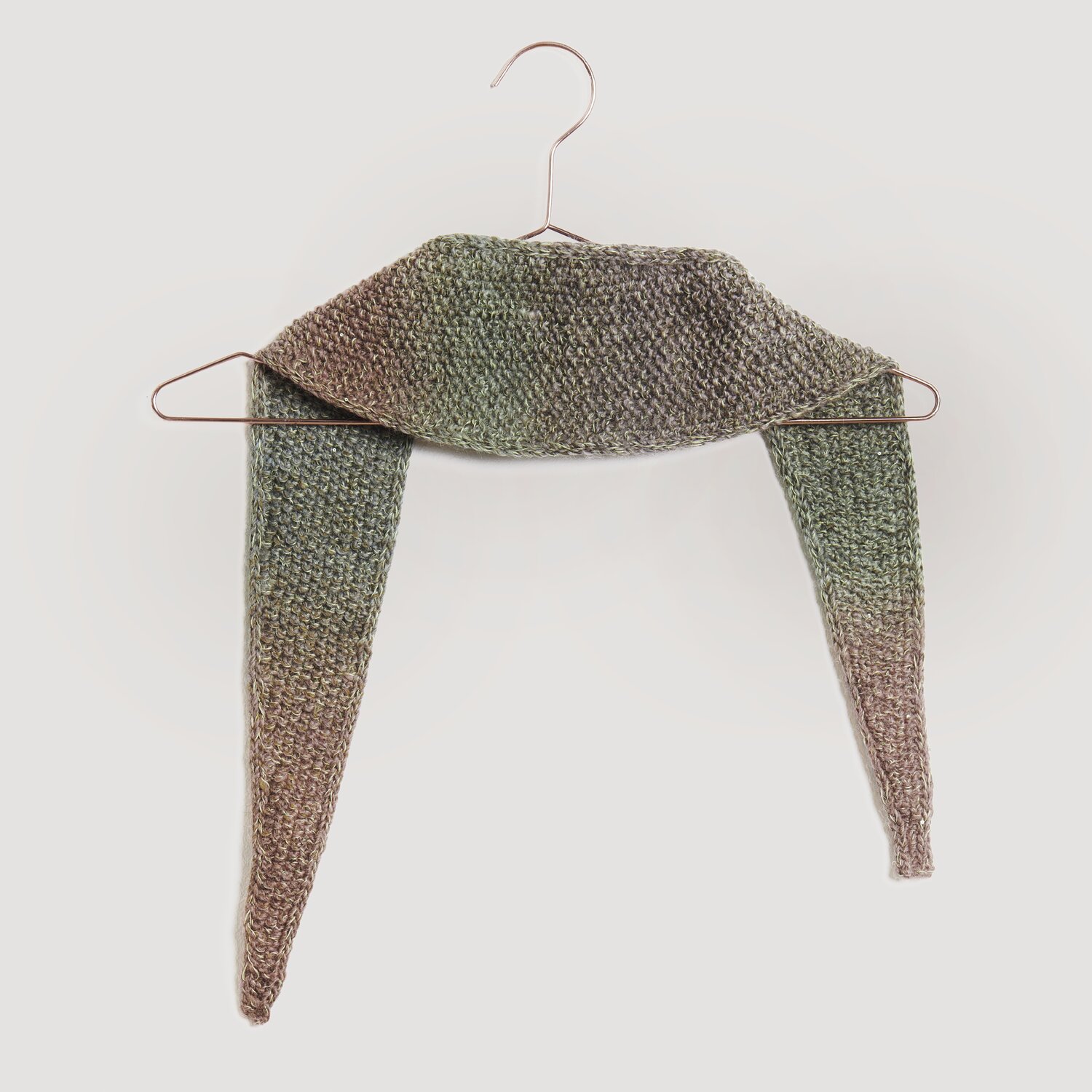 Brauner und grüner gestrickter Schal von Modell Legeware, drapiert auf einem Kleiderbügel. Der Schal zeigt ein dezentes Farbverlaufsmuster und ist ideal für kühle Tage.