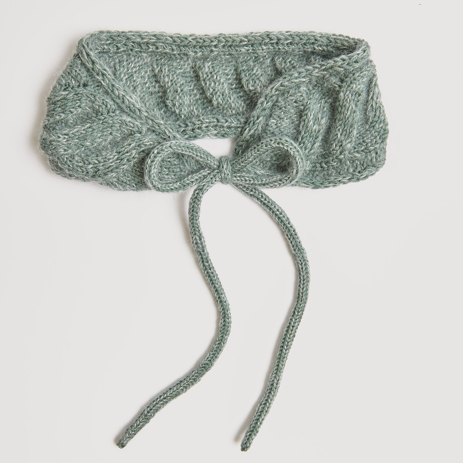 Essentials Merino dk: Eleganter, gestrickter Schal in Efeu-Grün mit dekorativer Schleife.