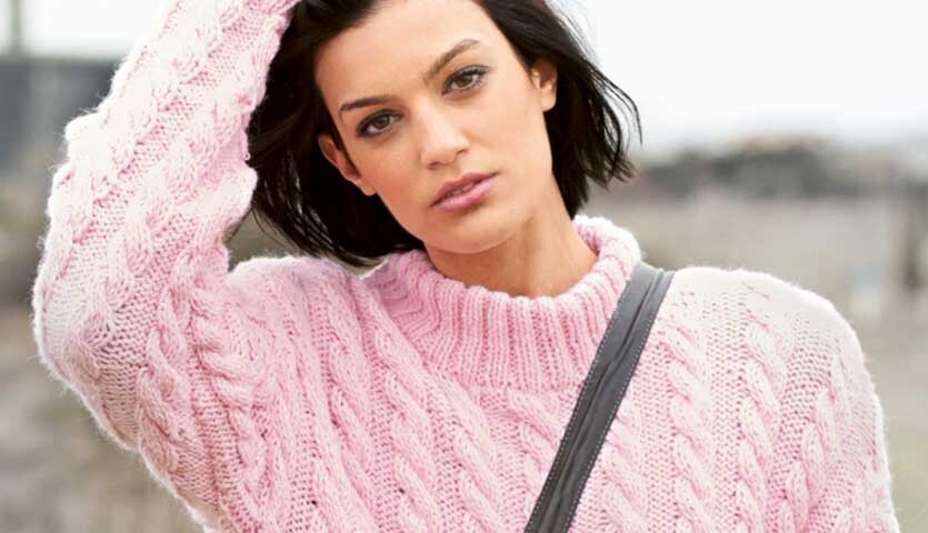 Strickanleitung Pullover aus Essentials Alpaca Blend chunky: Frau trägt rosa Zopfmuster-Pullover.