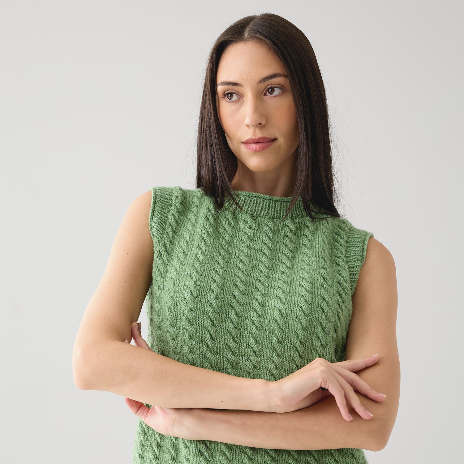 Strickset Top Modell 23 aus Die Neue Masche No. 15: Frau trägt grünes, ärmelloses Strickoberteil.