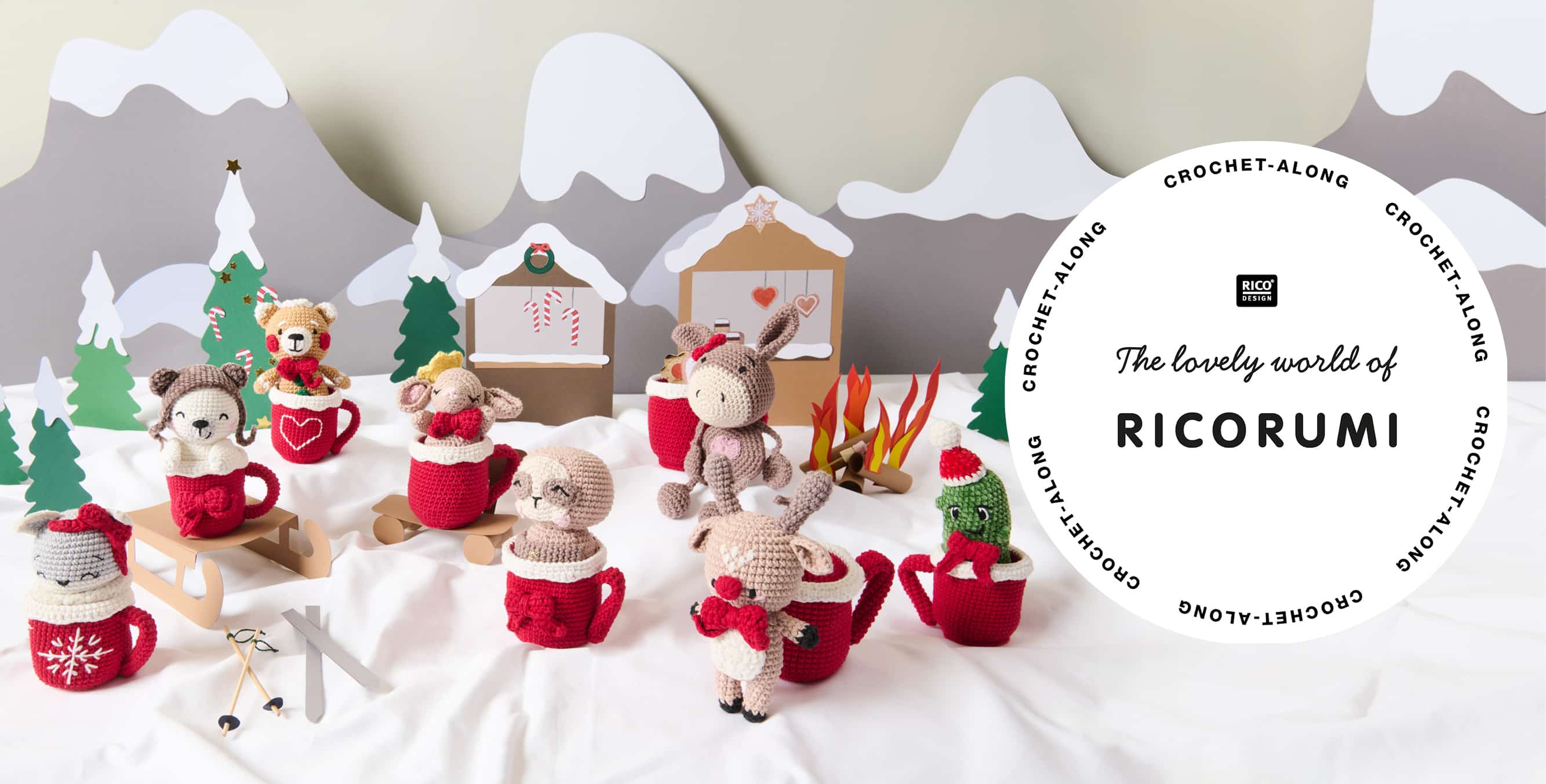 Acht Amigurumis mit gehäkelten Tassen sind in einer aus Papier gestalteten Winterlandschaft dekoriert. Ein Logo von Ricorumi ist abgebildet.