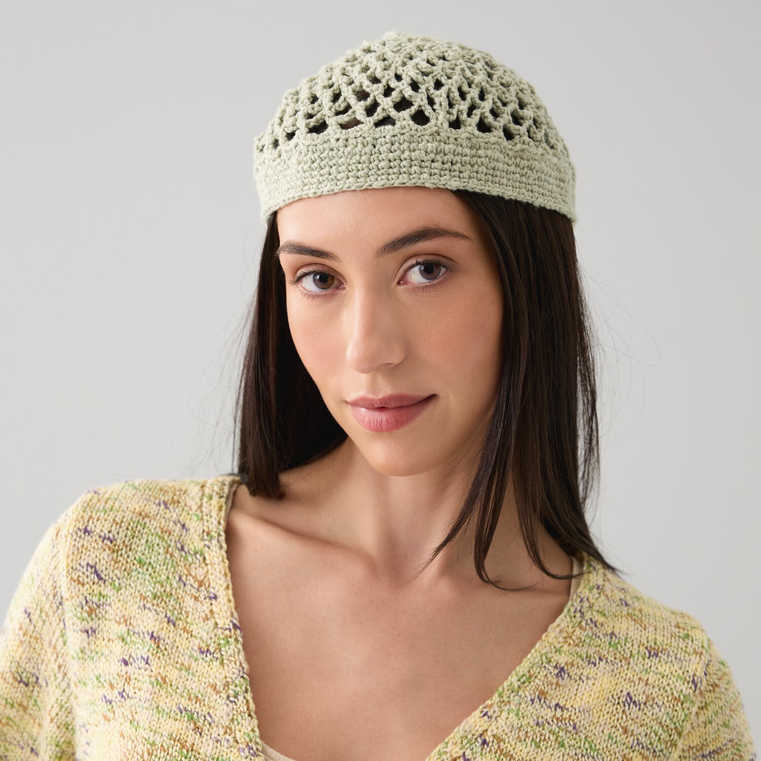 Häkelset Mütze Modell 26 aus Die Neue Masche No. 15: Frau trägt gehäkelte, grüne Mütze.