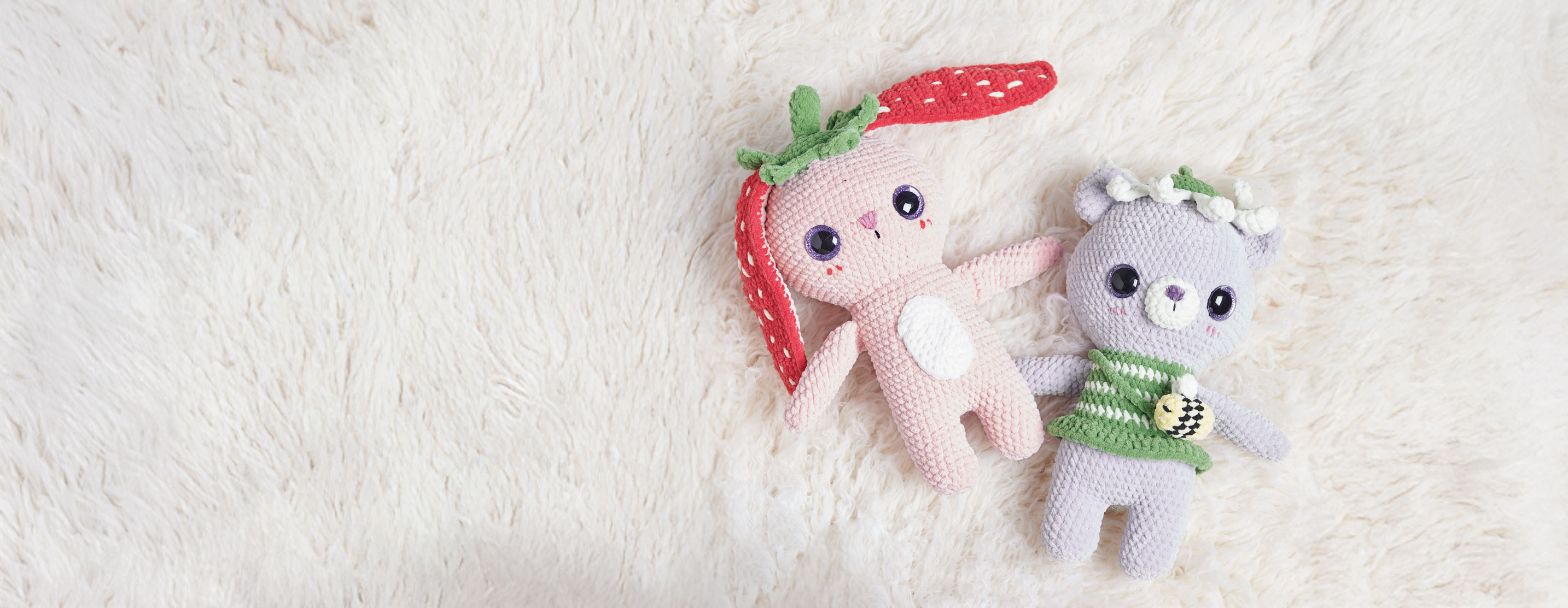 Gehäkelter Hase und gehäkelter Dinosaurier liegen auf hellem Teppich