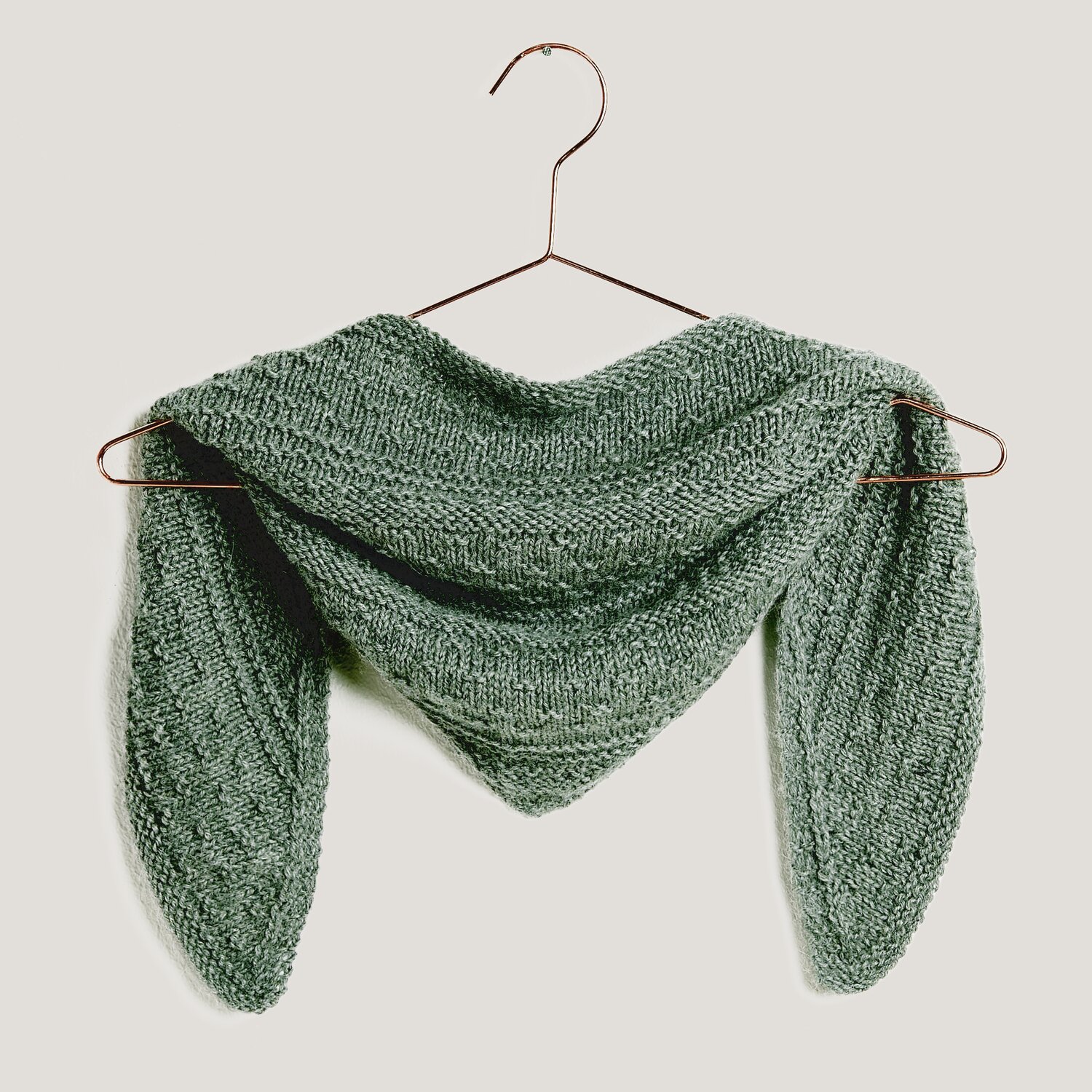 Strickset Mini Dreieckstuch Modell 02a aus Mini Tücher Special in Grau, drapiert auf einem Kleiderbügel vor neutralem Hintergrund.