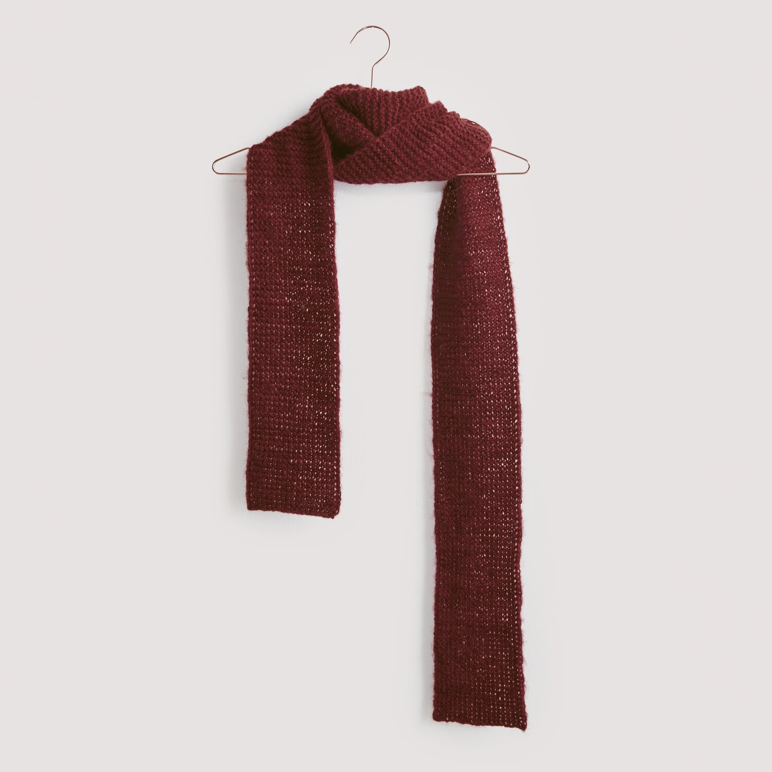 Strickset Schal Modell 17 aus Luxury Knits, dunkelroter Schal aus Premium Natural Fibres, hängt an einem Kleiderbügel vor grauem Hintergrund.