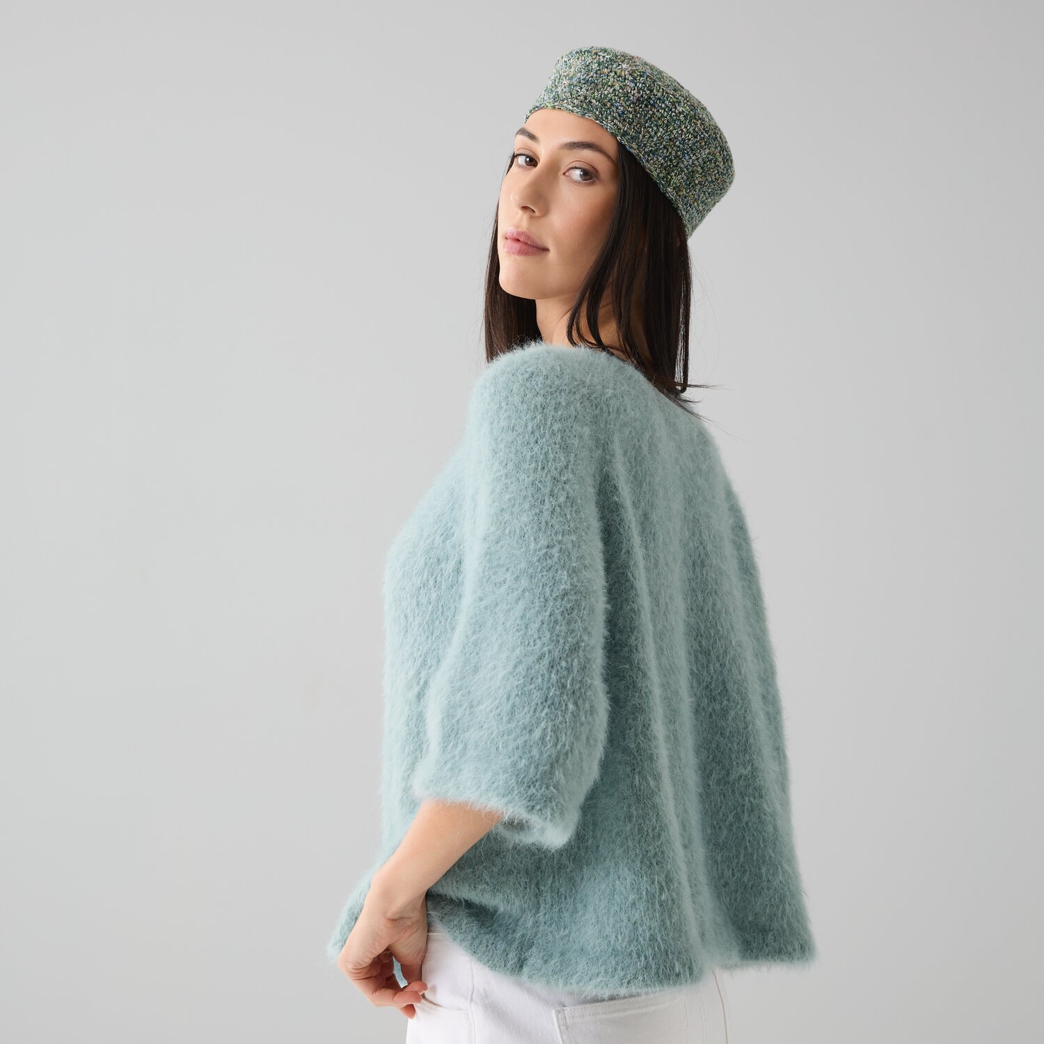 Strickset Shirt Modell 27 aus Die Neue Masche No. 15: Frau trägt flauschiges, hellblaues Shirt und gemusterten Hut. Ideal für stilvolle, gemütliche Outfits.