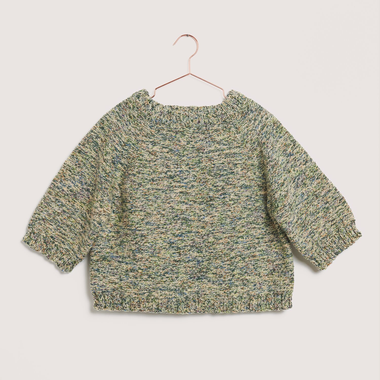 Made by Me No. 22 Frühjahr-Sommer Pullover in meliertem Grün auf einem Kleiderbügel.