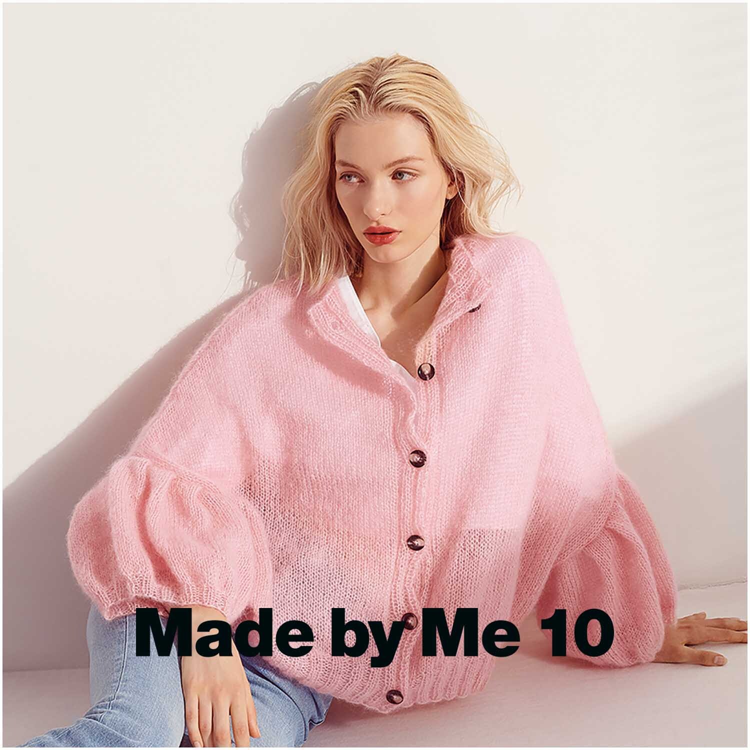 Essentials Super Kid Mohair Loves Silk: Frau in rosa Strickjacke von Rico Design, sitzt entspannt auf hellem Hintergrund.