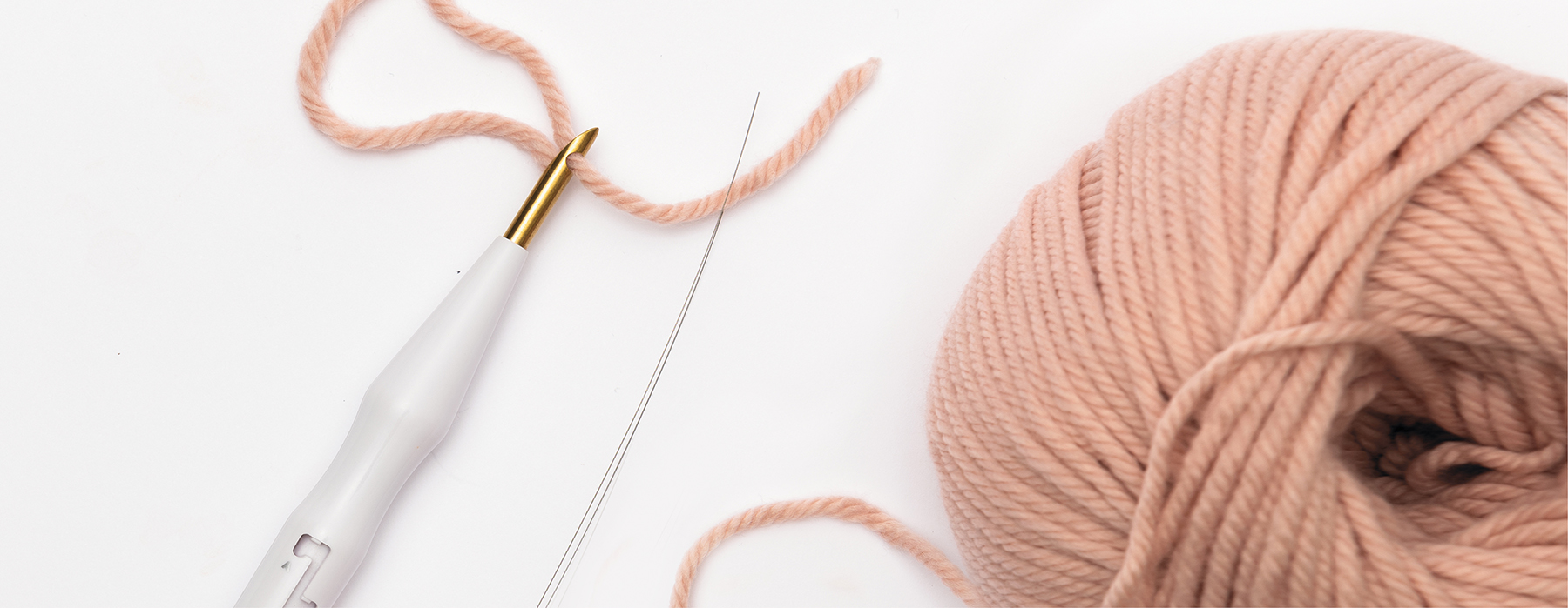 Punch Needle und rosa Wollknäuel auf weißem Hintergrund
