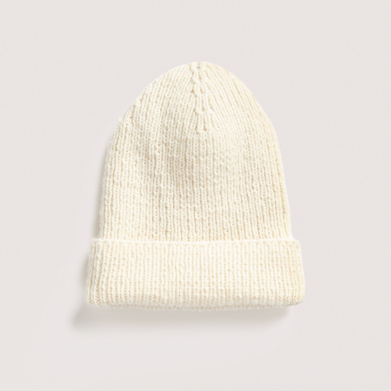 Strickset Mütze Modell 06 aus Luxury Knits: Cremefarbene, handgestrickte Mütze aus hochwertigen Naturfasern auf hellem Hintergrund.