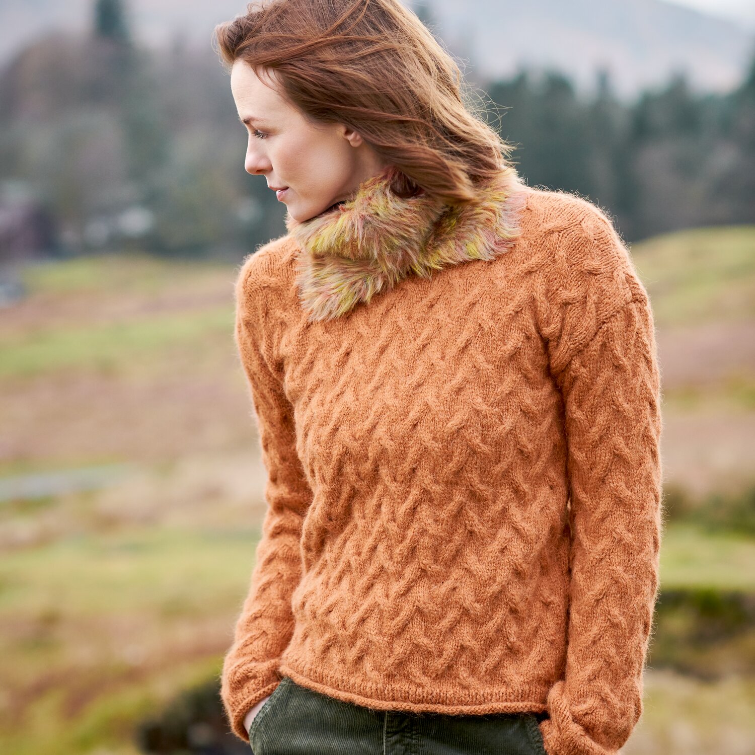 Strickset Kragen Modell 28b aus Lovewool No. 23, gestrickter Pullover mit Strukturmuster, warmes Herbstton-Garn, getragen von Frau in Landschaft im Freien