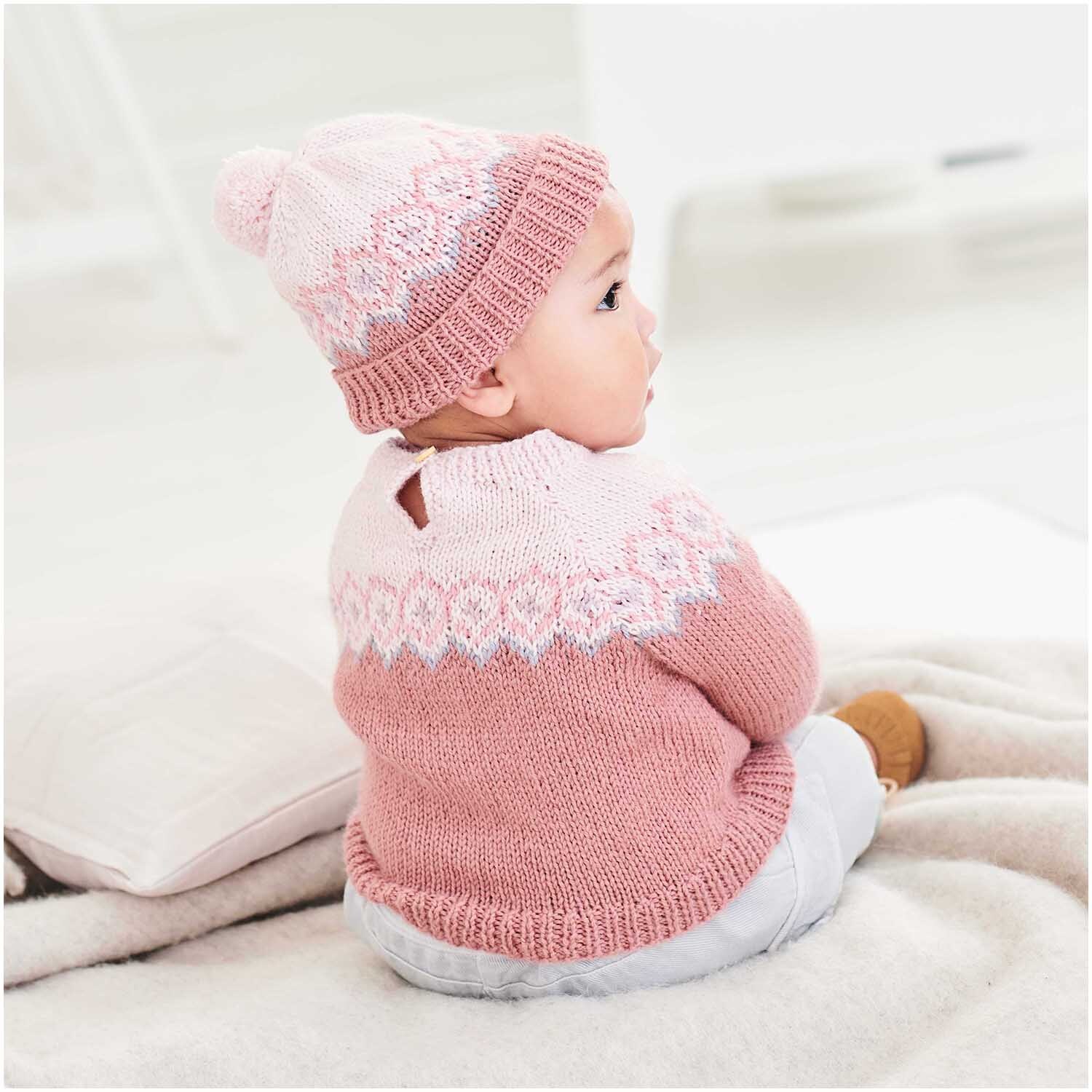 Rico Baby Dream dk uni - A Luxury Touch: Baby in gestricktem Flieder-Outfit von Rico Design, sitzt auf einer Decke.