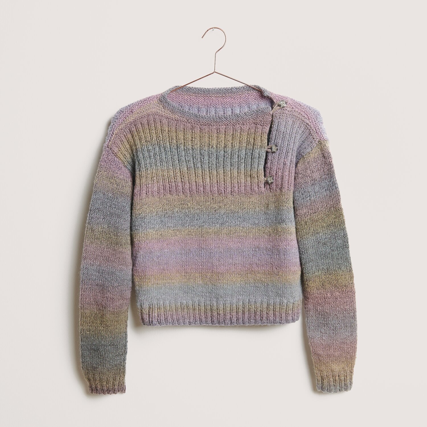 Creative Melange Alpaca Wonderball dk 100g 300m Farbe Pastels von Rico Design Creative Melange Alpaca Wonderball dk Pullover in Pastelltönen, gestrickt mit Rico Design Wolle, zeigt dezente Streifen und Knopfdetails auf der Schulter.