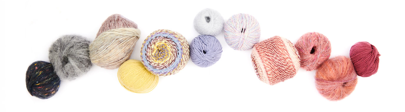 Verschiedene Garne farblich sortiert und aneinandergereiht. Flatlay von Produkten.