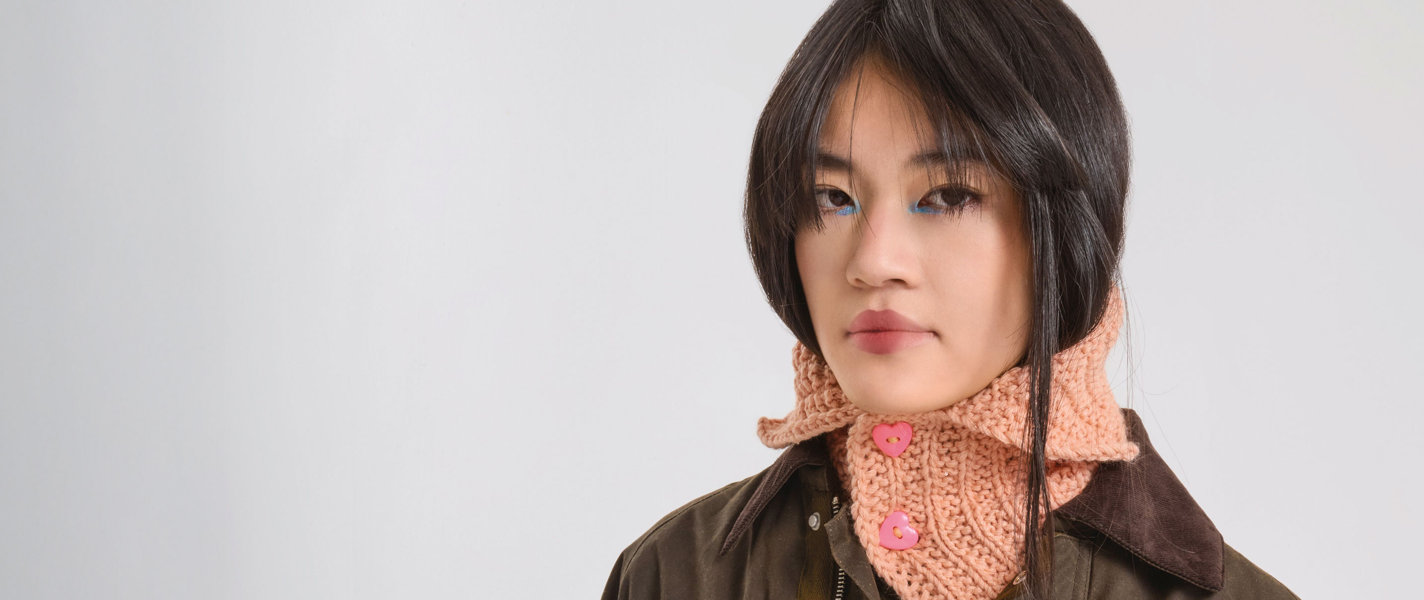 Frau trägt apricotfarbenen Schalkragen mit pinken Herz-Knöpfen