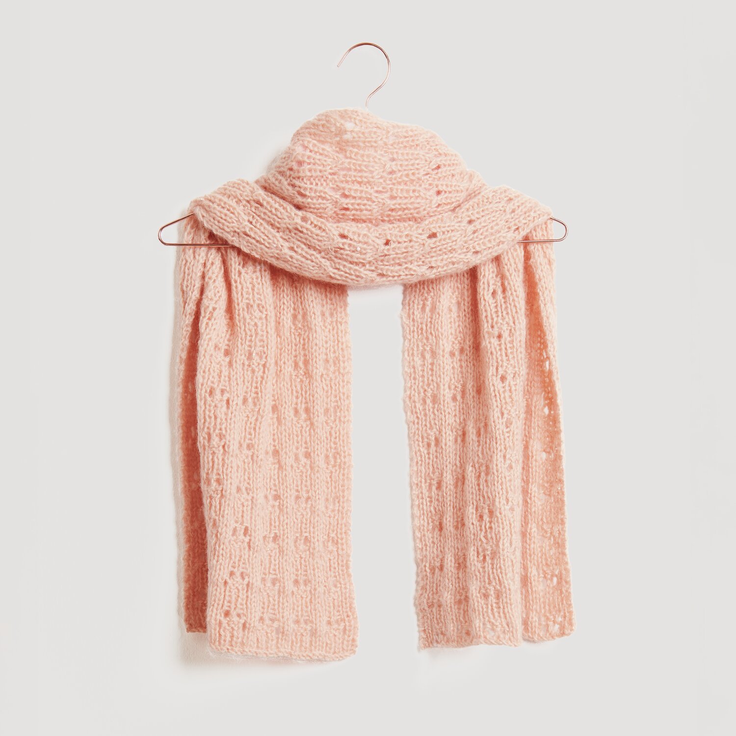 Ein weicher, rosa Strickschal hängt auf einem Kleiderbügel. Der Schal ist von der Marke Modell Legeware und besticht durch sein elegantes Design. Perfekt für kühle Tage.