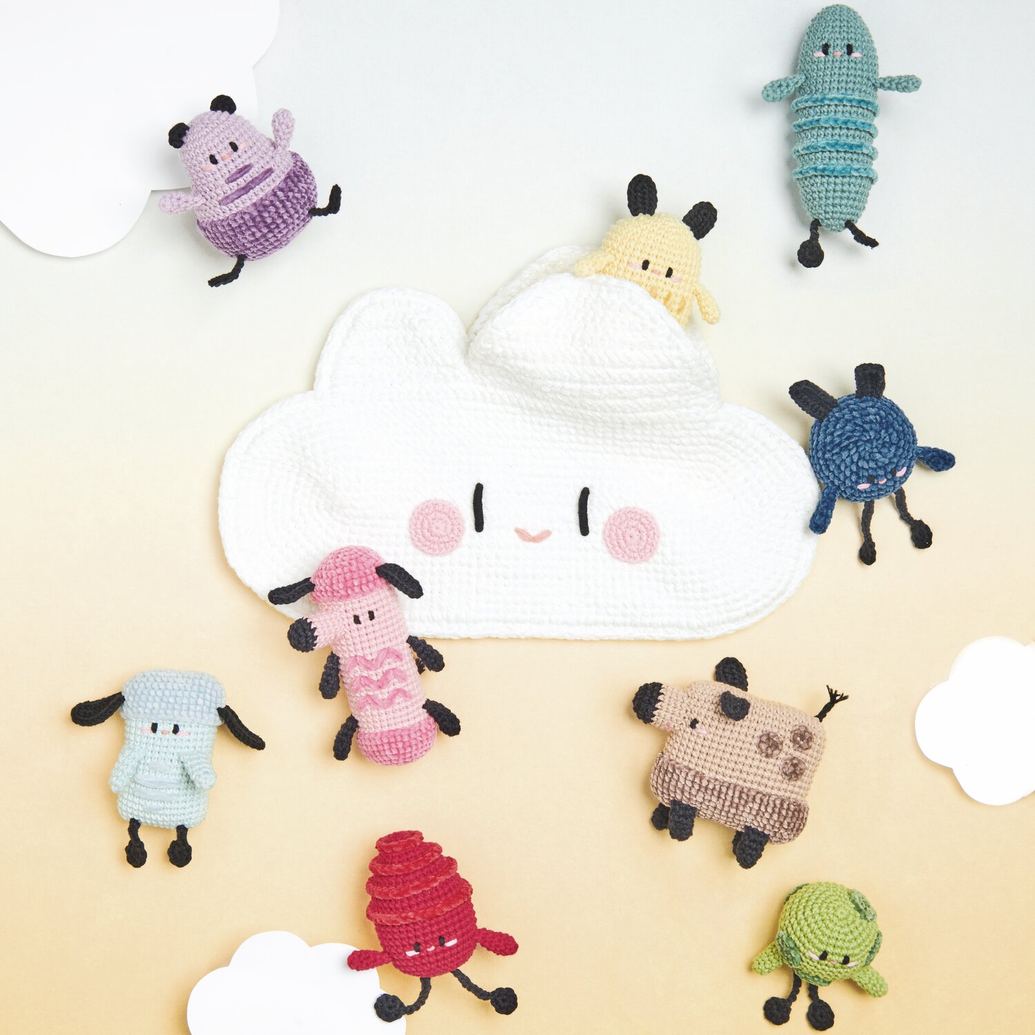 Ricorumi Rainbow Weirdos: Bunte, gehäkelte Figuren von Rico Design umgeben eine lächelnde Wolke.