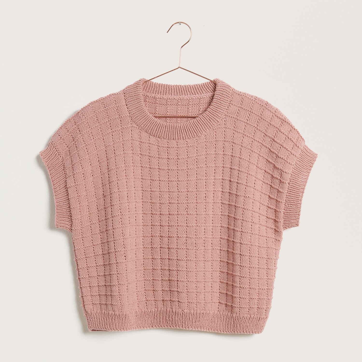 Strickset Shirt Modell 15 aus Die Neue Masche Nr. 9, ein rosa gestricktes Oberteil auf einem Kleiderbügel.