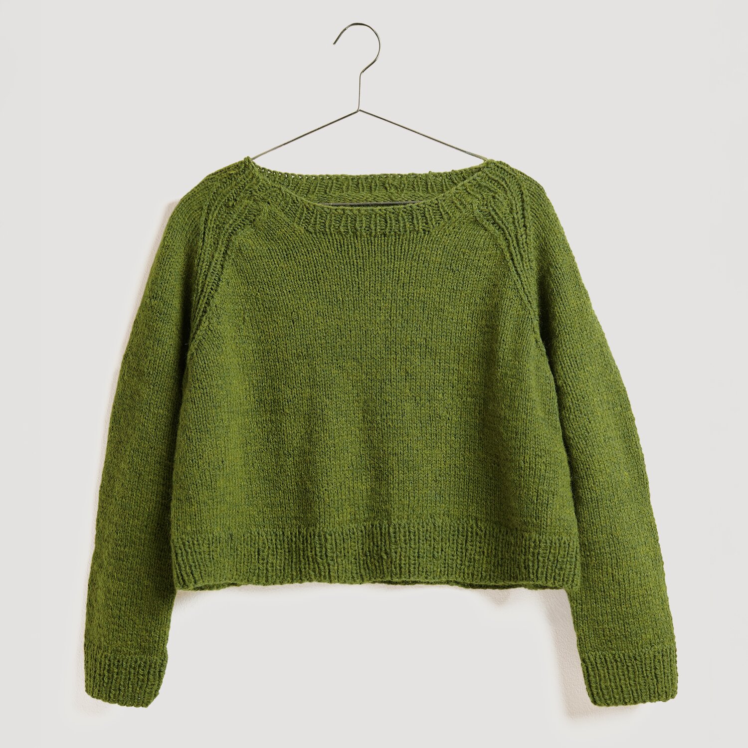 Strickset Pullover Modell 20 aus Die Neue Masche No. 13, olivgrün, aus Soft Alpaca, hängt an einem Kleiderbügel.