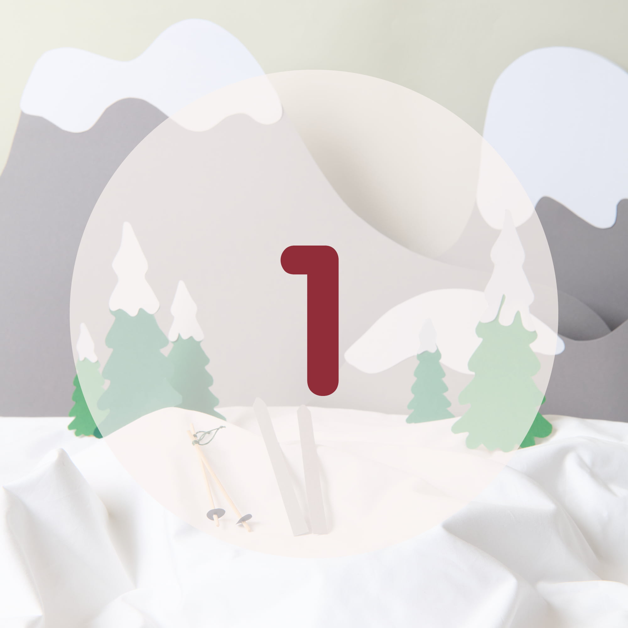 Die Zahl 1 steht in der Mitte vor einer aus Papier gestalteten Schneelandschaft