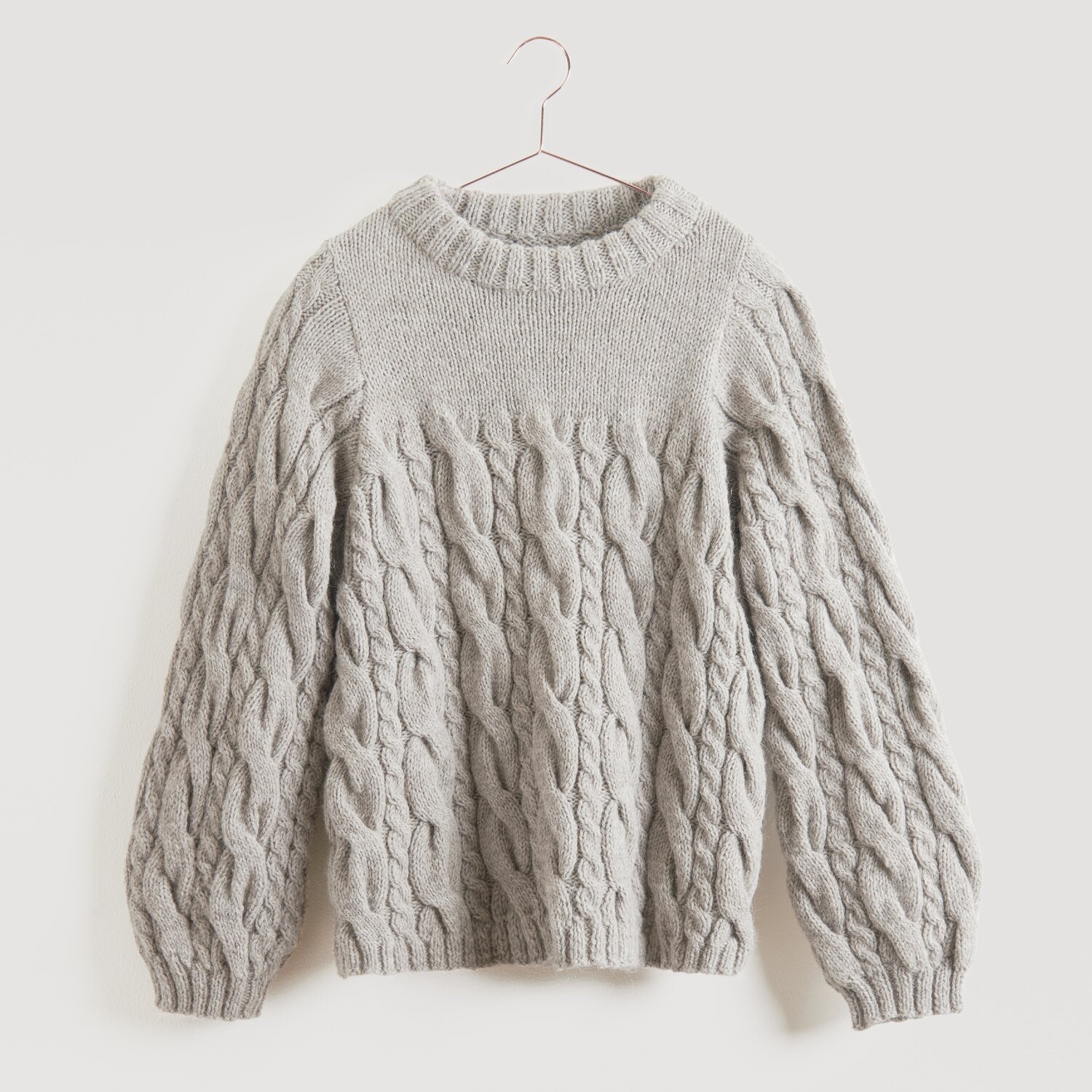 Grauer Strickpullover von Modell Legeware, aufgehängt an einem Kleiderbügel. Der Pullover hat ein Zopfmuster und lange Ärmel, ideal für kühle Tage. Perfekt für einen lässigen, stilvollen Look.