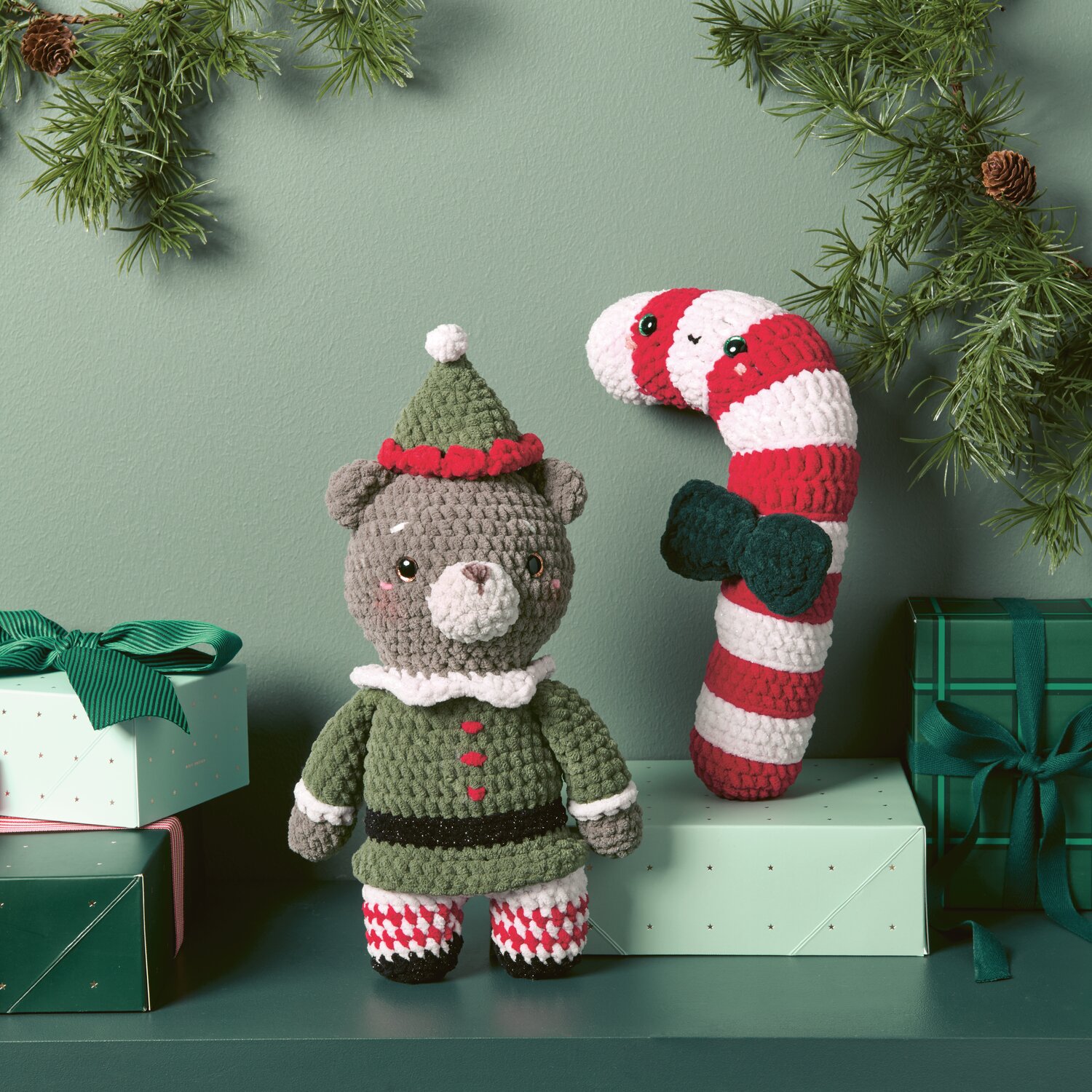 Creative Chenillove 100g 110m Farbe Natur von Rico Design Chenillove Christmas: Niedlicher gehäkelter Bär in Oliv mit Zuckerstange, umgeben von Geschenken.