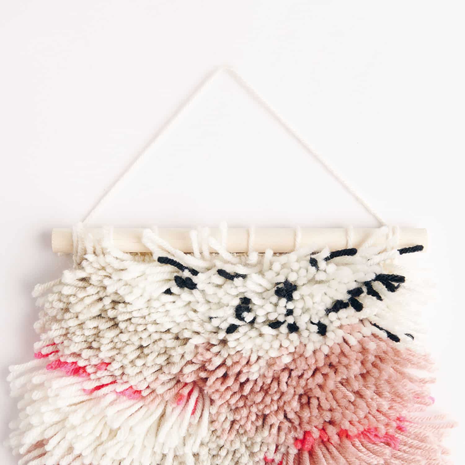 Geknüpfter Wandbehang hängt vor einer weißen Wand