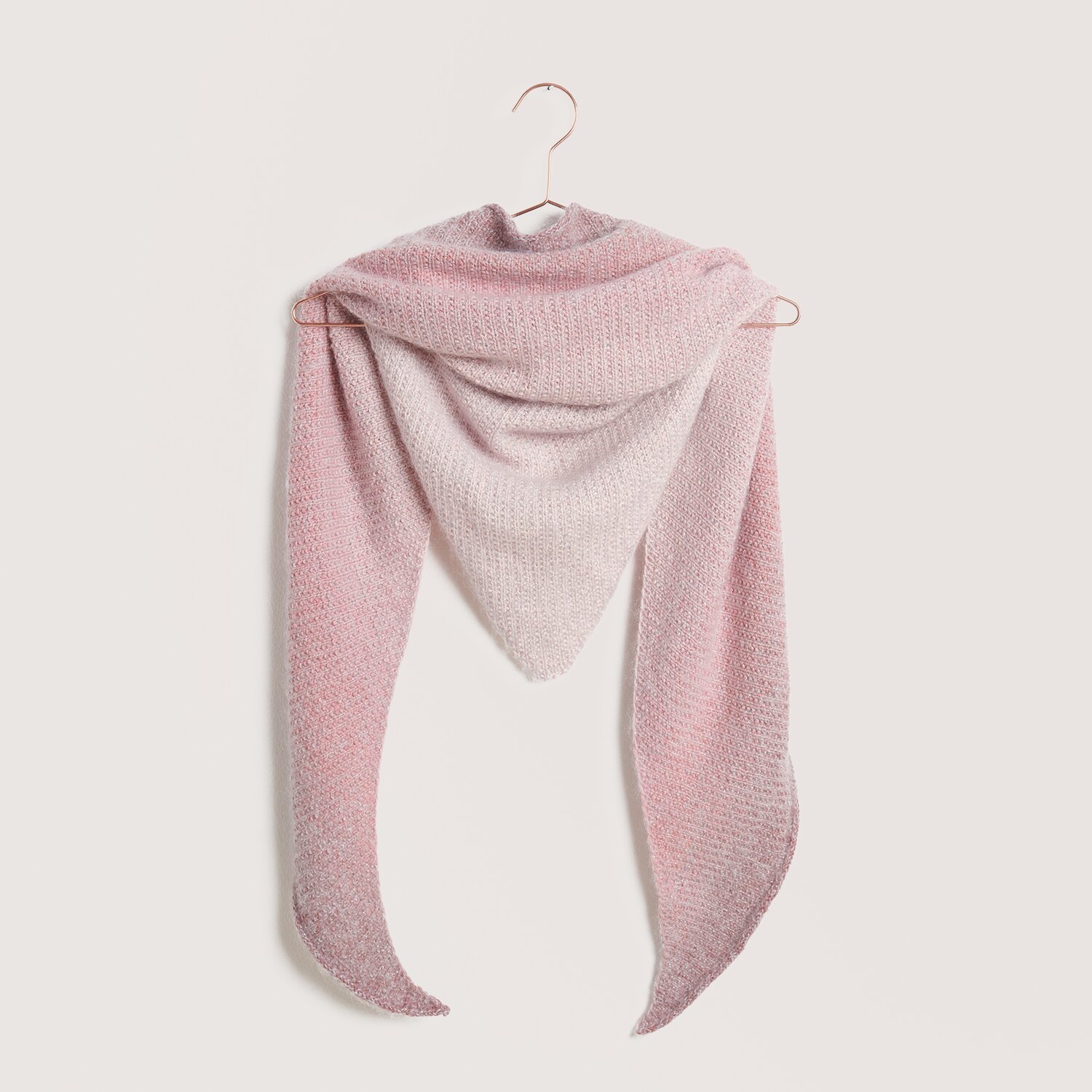 Strickset Dreieckstuch Modell 13: Elegantes Tuch in sanften Rosa- und Grautönen, aufgehängt an einem Haken. Ideal für Frühling und Sommer.