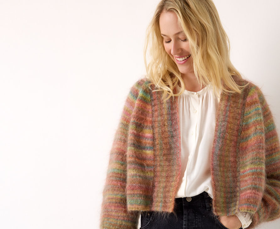 Frau trägt eine bräunliche Strickjacke mit Farbverlauf vor einem neutralen Hintergrund